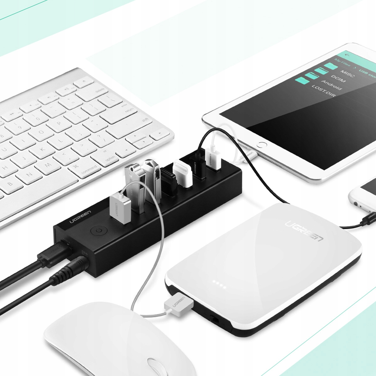 Ein schwarzer USB-Hub mit mehreren angeschlossenen Geräten: Tastatur, Tablet, Maus und Telefon.