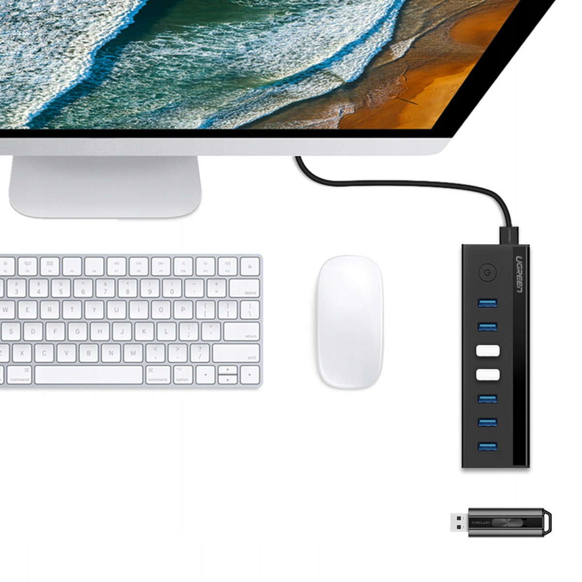 Ein weißer Computermonitor mit Tastatur und Maus. Ein schwarzer USB-Hub befindet sich neben dem Monitor auf einer weißen Oberfläche.