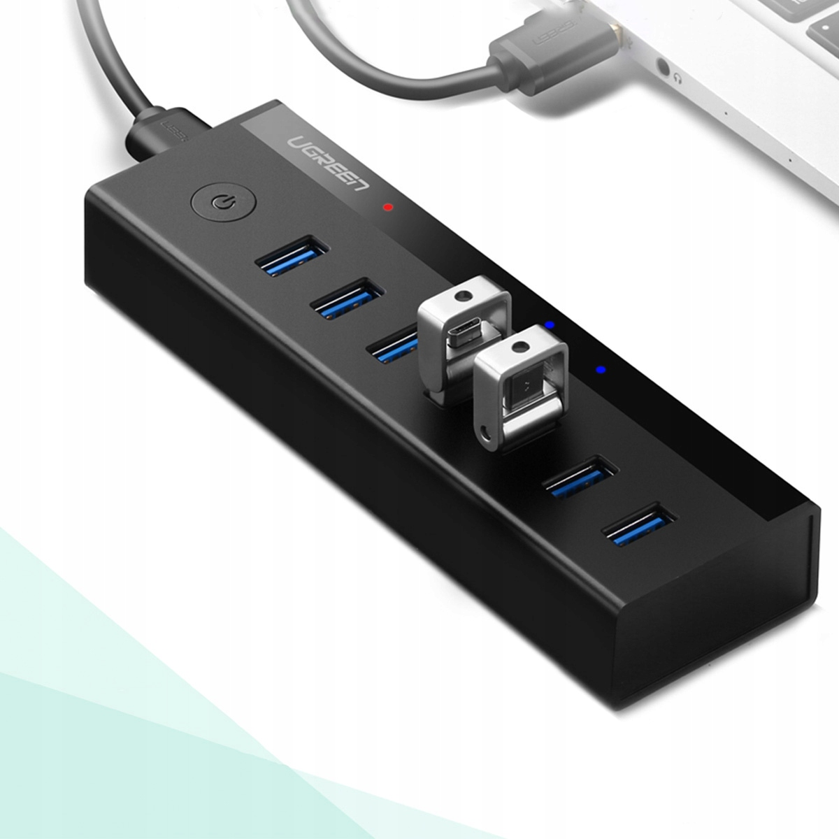 Ein schwarzer USB-Hub mit mehreren USB-Anschlüssen, zwei silbernen Metallteilen und einem angeschlossenen Laptop-Kabel.