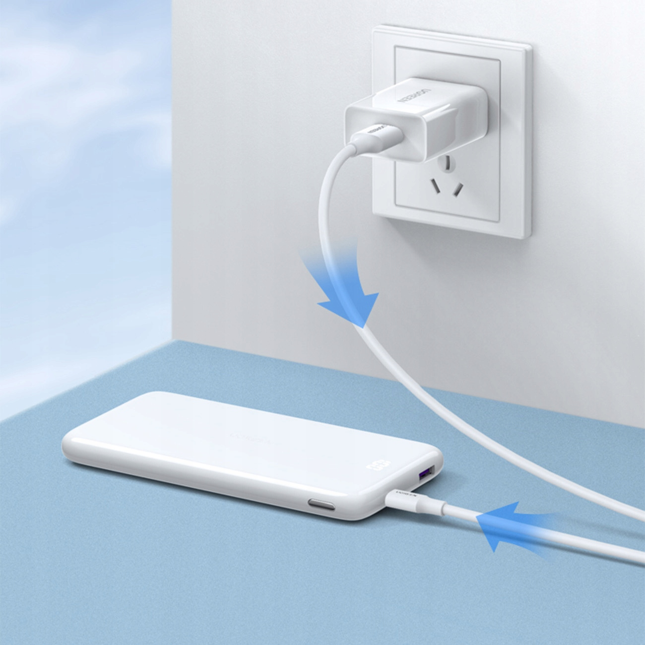 Telefon i power bank podłączone kablem do gniazdka ściennego.