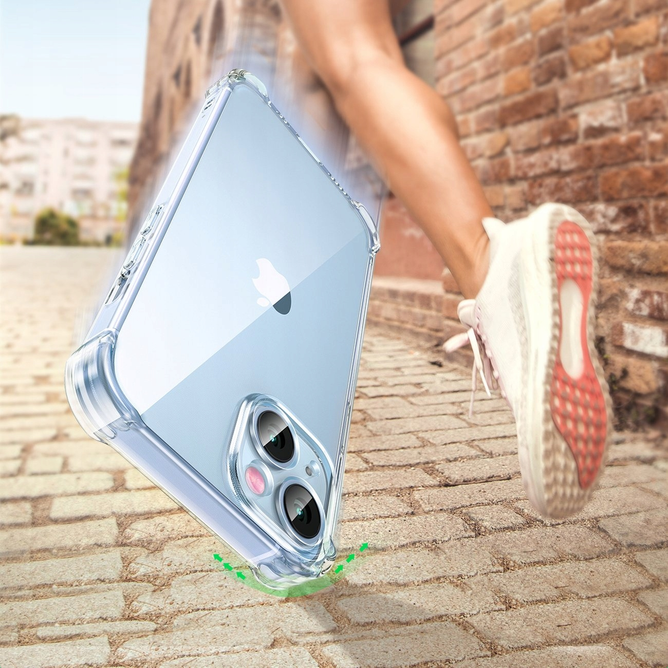 Una custodia trasparente per telefono su un marciapiede di mattoni calpestata da una scarpa da ginnastica. Freccia verde indica il punto d'impatto.