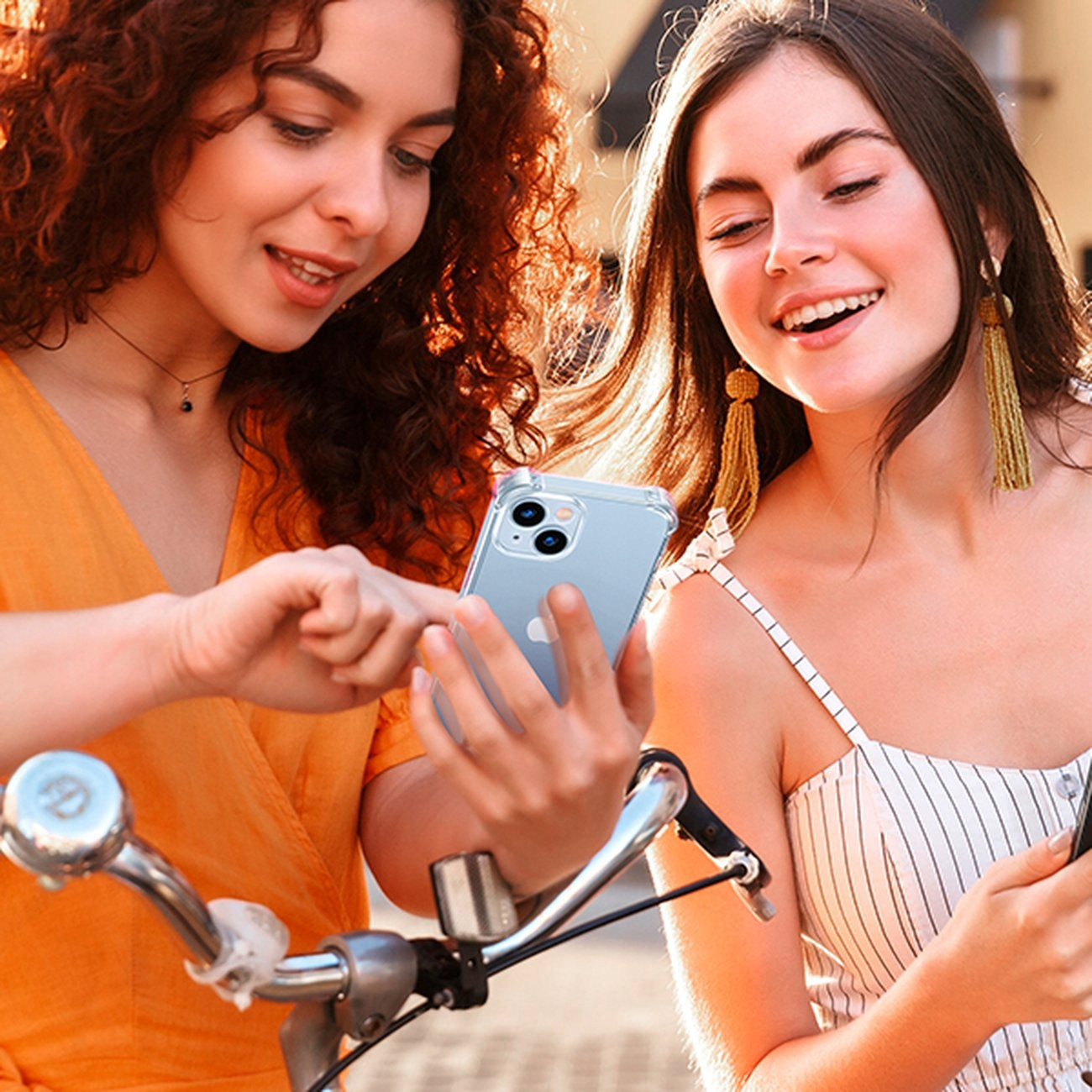 Due donne che guardano un telefono. Una tiene il telefono, l'altra indica lo schermo.