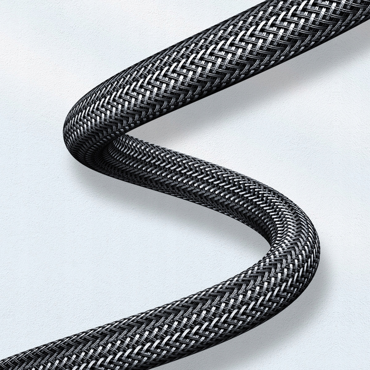 Pleciony czarny kabel. Kabel jest falisty. Białe tło.