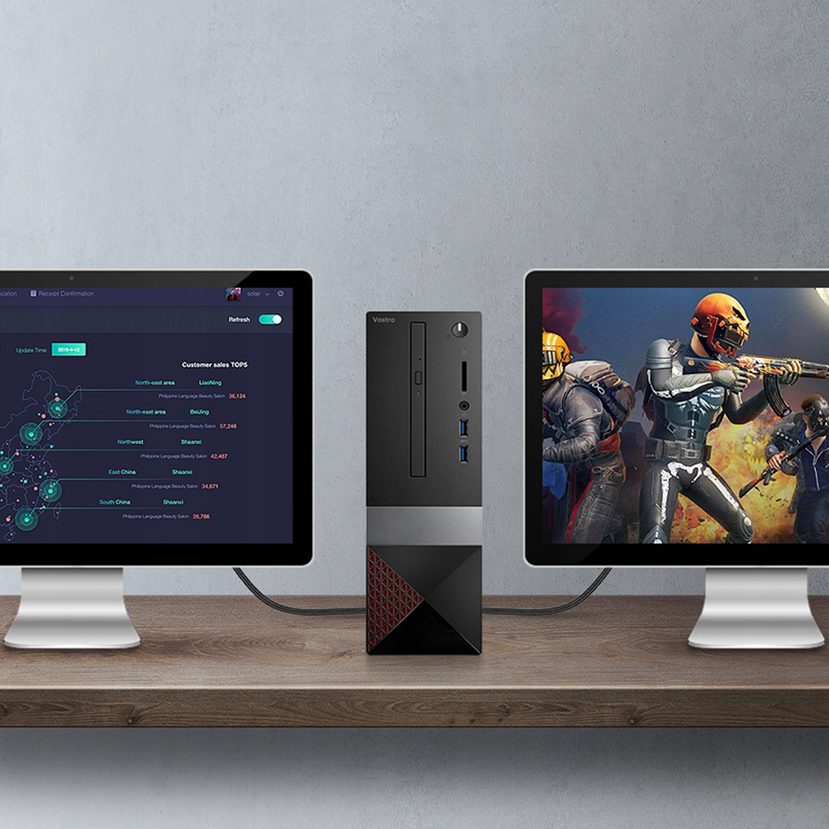 Dwa monitory i komputer pośrodku na drewnianym biurku, pokazujące grę i wykresy.