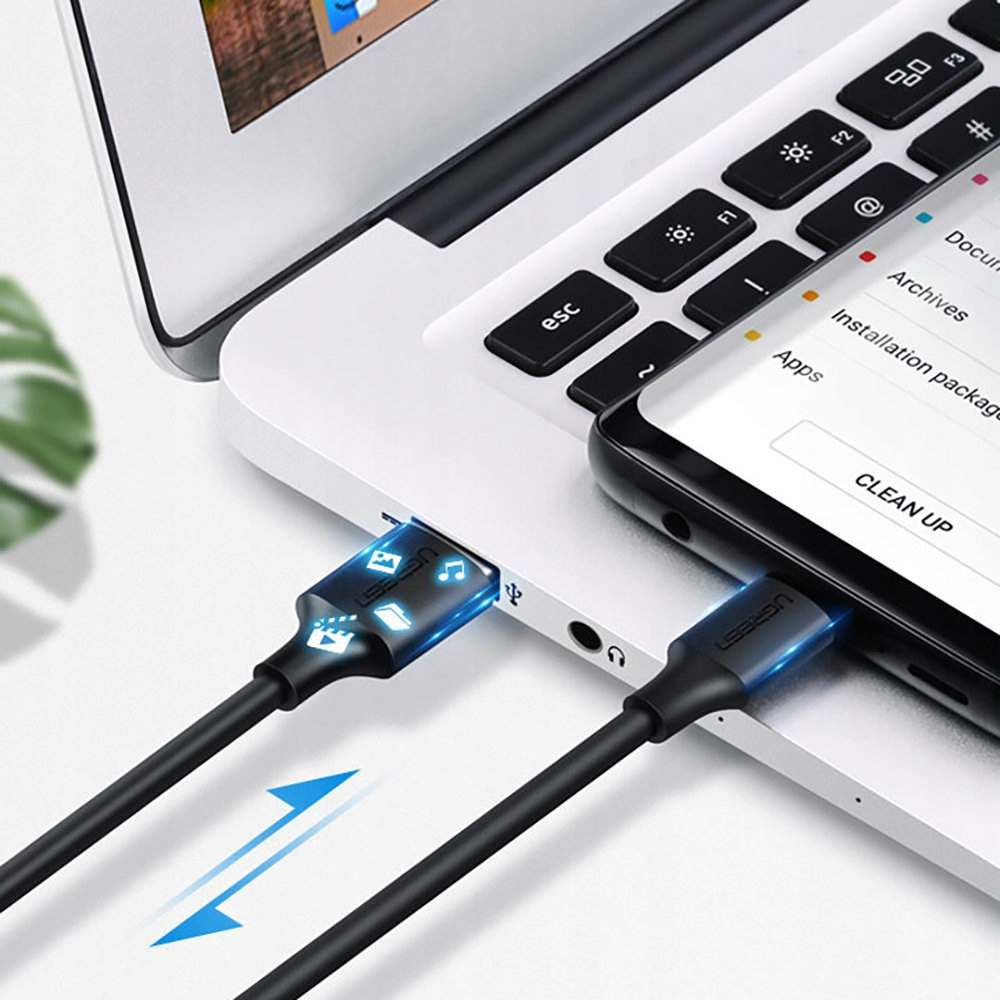 Laptop und Telefon mit angeschlossenen Kabeln. Telefonbildschirm zeigt Datenübertragungssymbole. Blaue Pfeile zeigen Richtung.