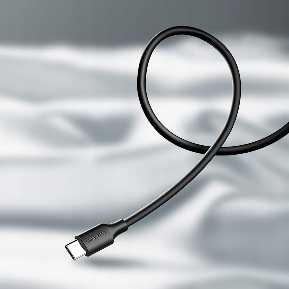 Ein geschlungenes schwarzes USB-C-Kabel mit dem UGREEN-Logo auf dem Stecker, vor hellgrauem Hintergrund.