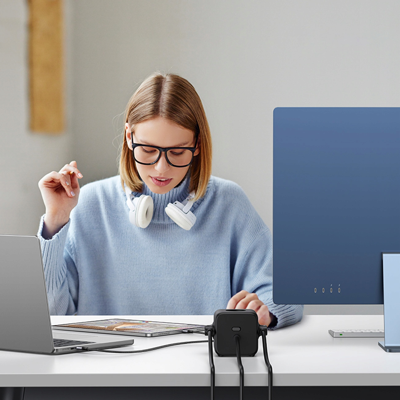 Kobieta w okularach używająca laptopa i huba z podłączonymi urządzeniami.