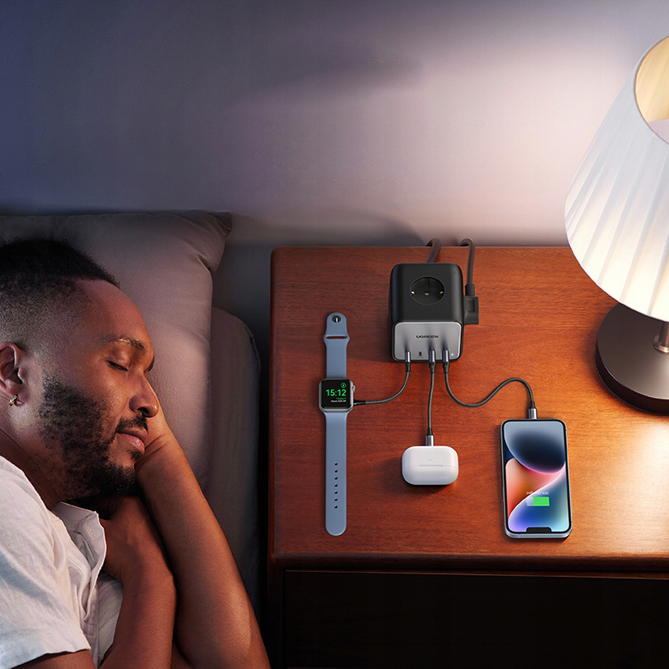 Mężczyzna śpi obok stolika nocnego z urządzeniami ładującymi.
