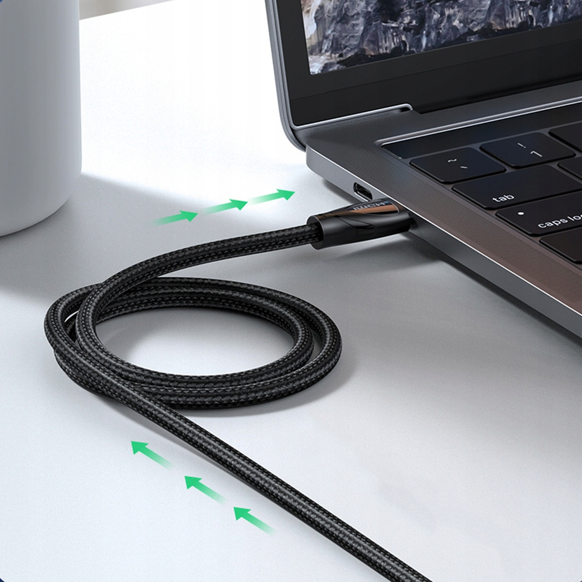 Laptop z podłączonym czarnym kablem, zielone strzałki wskazują kierunek kabla.