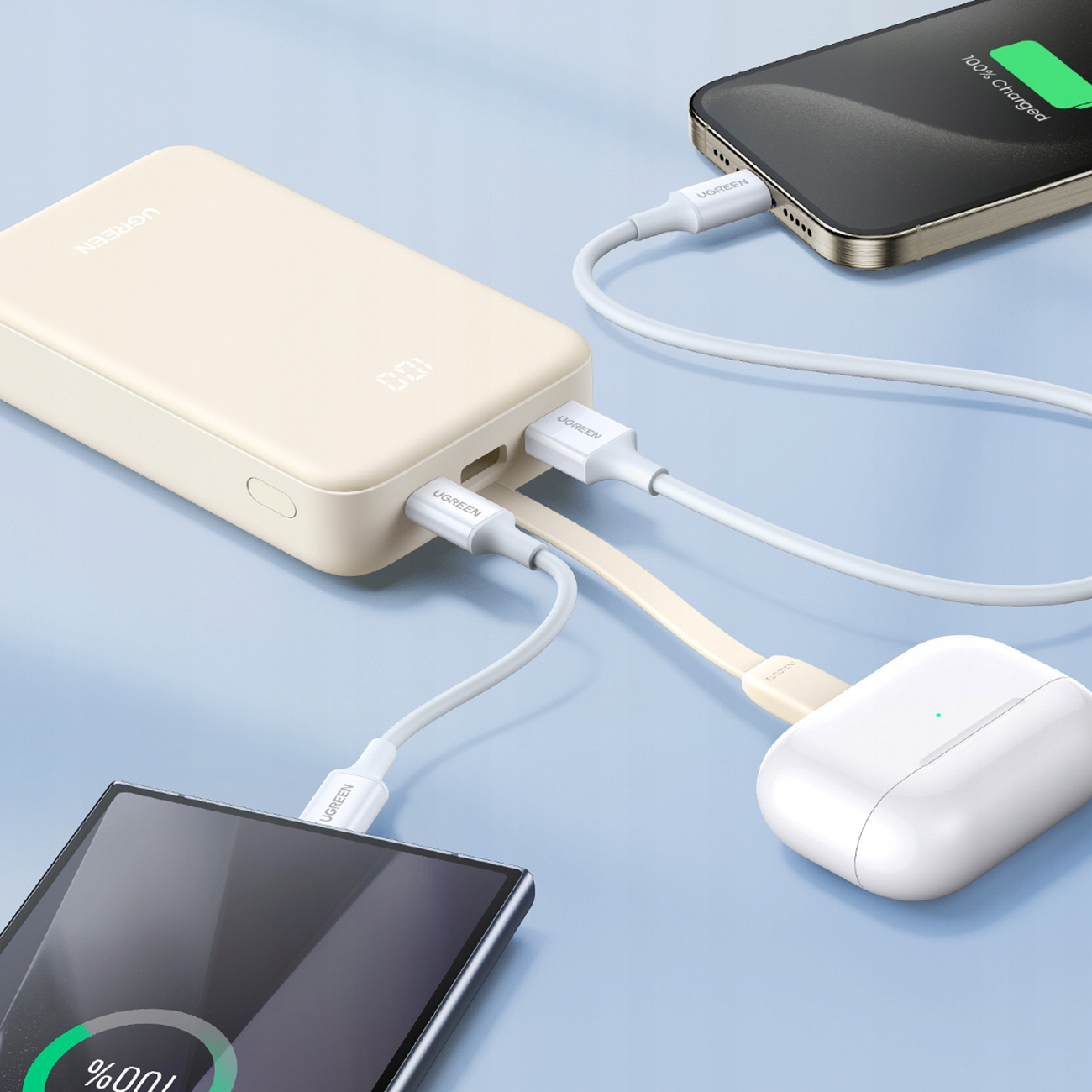 Beige powerbank laadt drie apparaten op: telefoon, oortelefoon en een andere telefoon. Witte kabels verbinden ze.