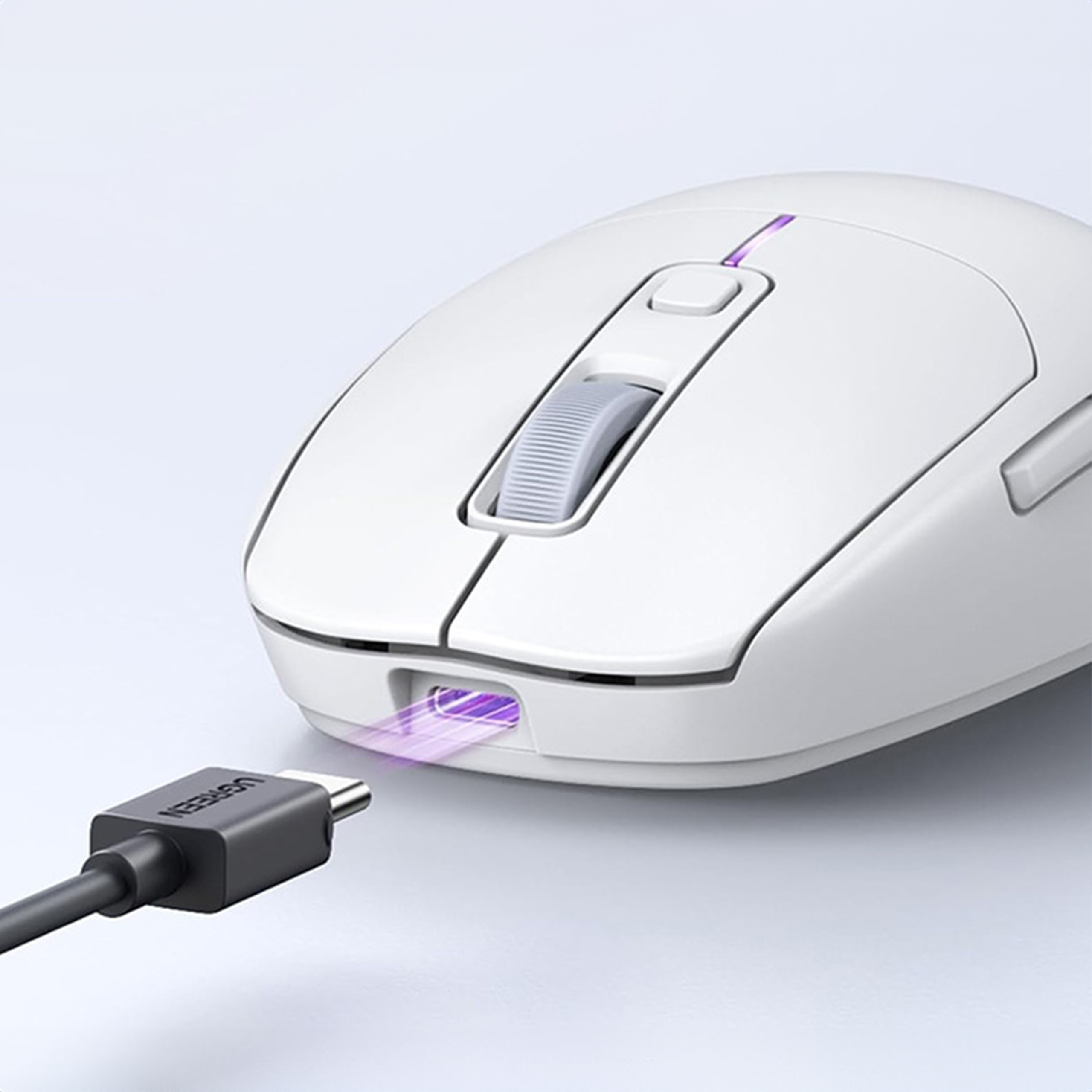 Eine weiße Maus mit eingestecktem Ladekabel. Die Maus hat ein Scrollrad und zwei Seitentasten. UGREEN ist auf dem Kabel.