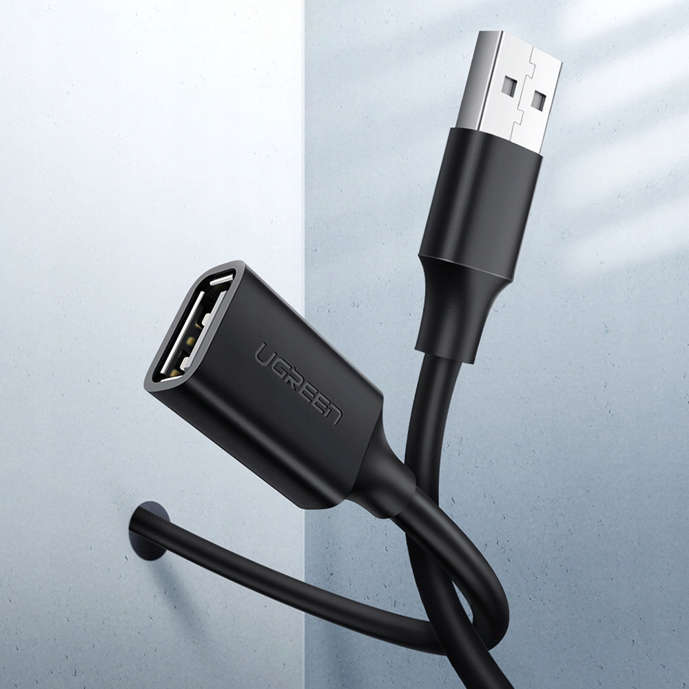 Zbliżenie czarnego kabla UGREEN z USB i portem USB żeńskim. Kabel przylega do ściany.