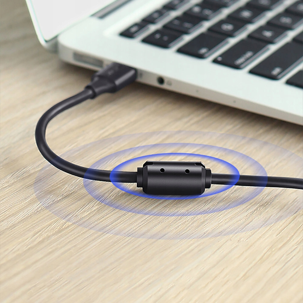 Czarny kabel USB jest podłączony do laptopa. Na kablu znajduje się czarny pierścień magnetyczny redukujący szumy.