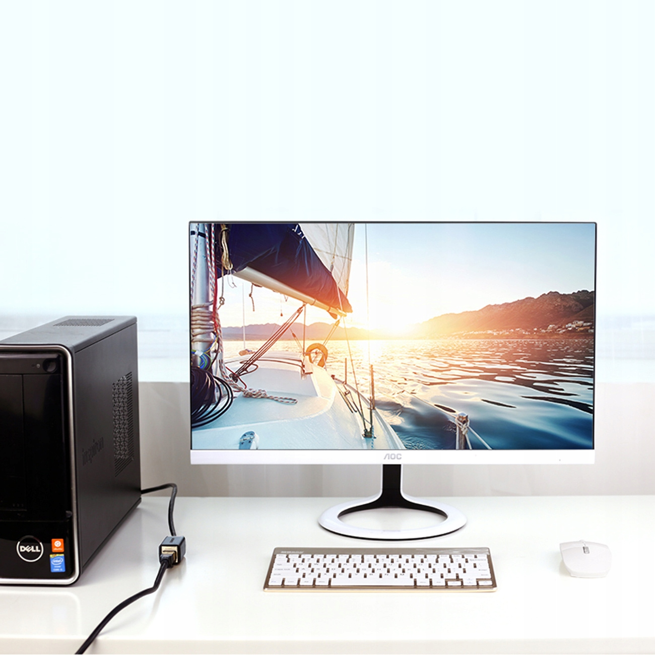 Konfiguracja komputera z monitorem, klawiaturą, myszą i czarną obudową PC na białym biurku. Zachód słońca.