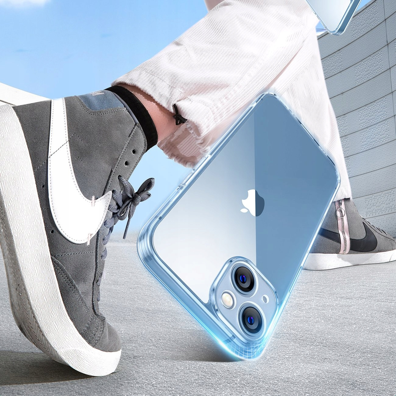 Persona che cammina su superficie di cemento con scarpe grigie e custodia per telefono. Cielo blu sullo sfondo.
