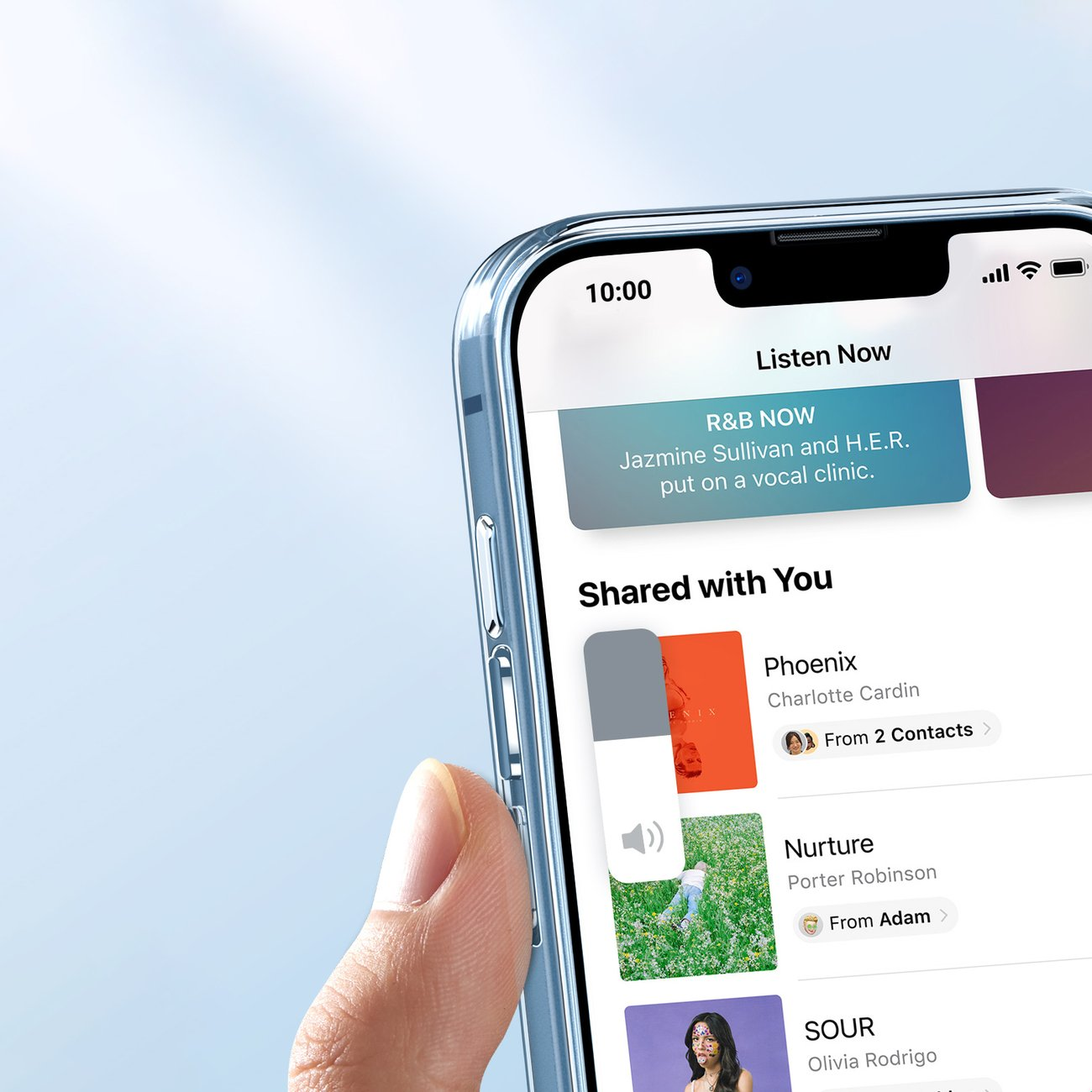 Una mano che tiene un telefono con una custodia trasparente. Lo schermo del telefono mostra un'interfaccia di un'app musicale. Lo sfondo è sfocato.