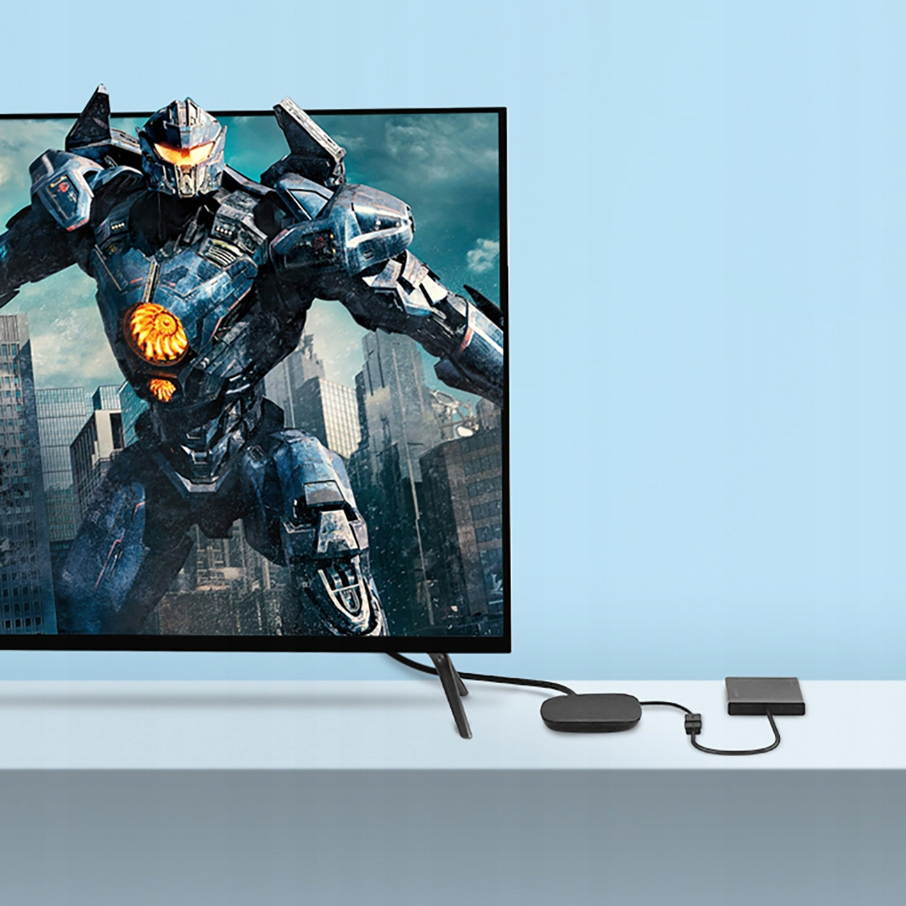 Tv met een robotscène. Een zwarte kabel en een zwarte doos op de witte tafel.
