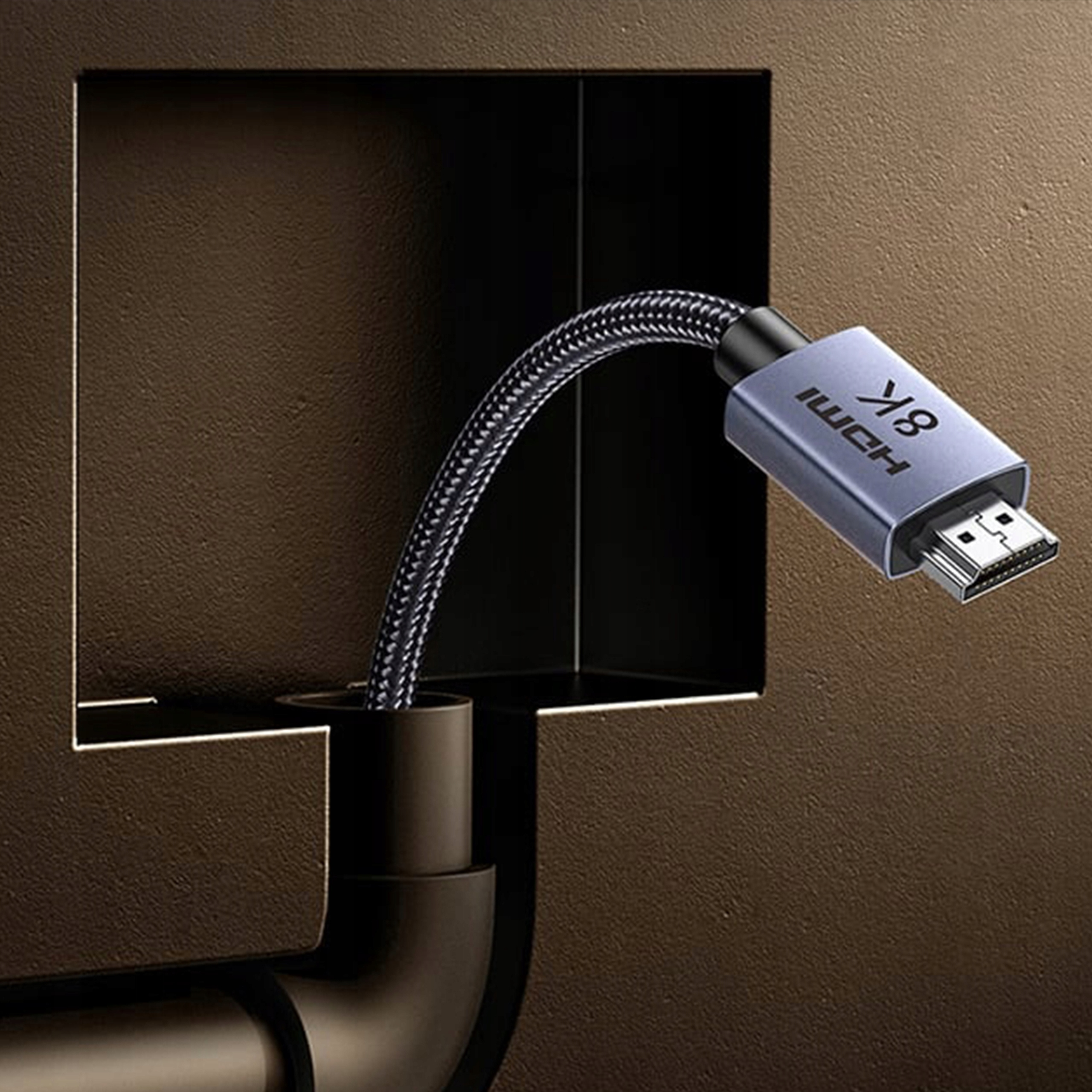 Zbliżenie kabla HDMI z etykietą 8K. Kabel jest podłączony do gniazdka ściennego. Tło to ciemnobrązowa ściana.