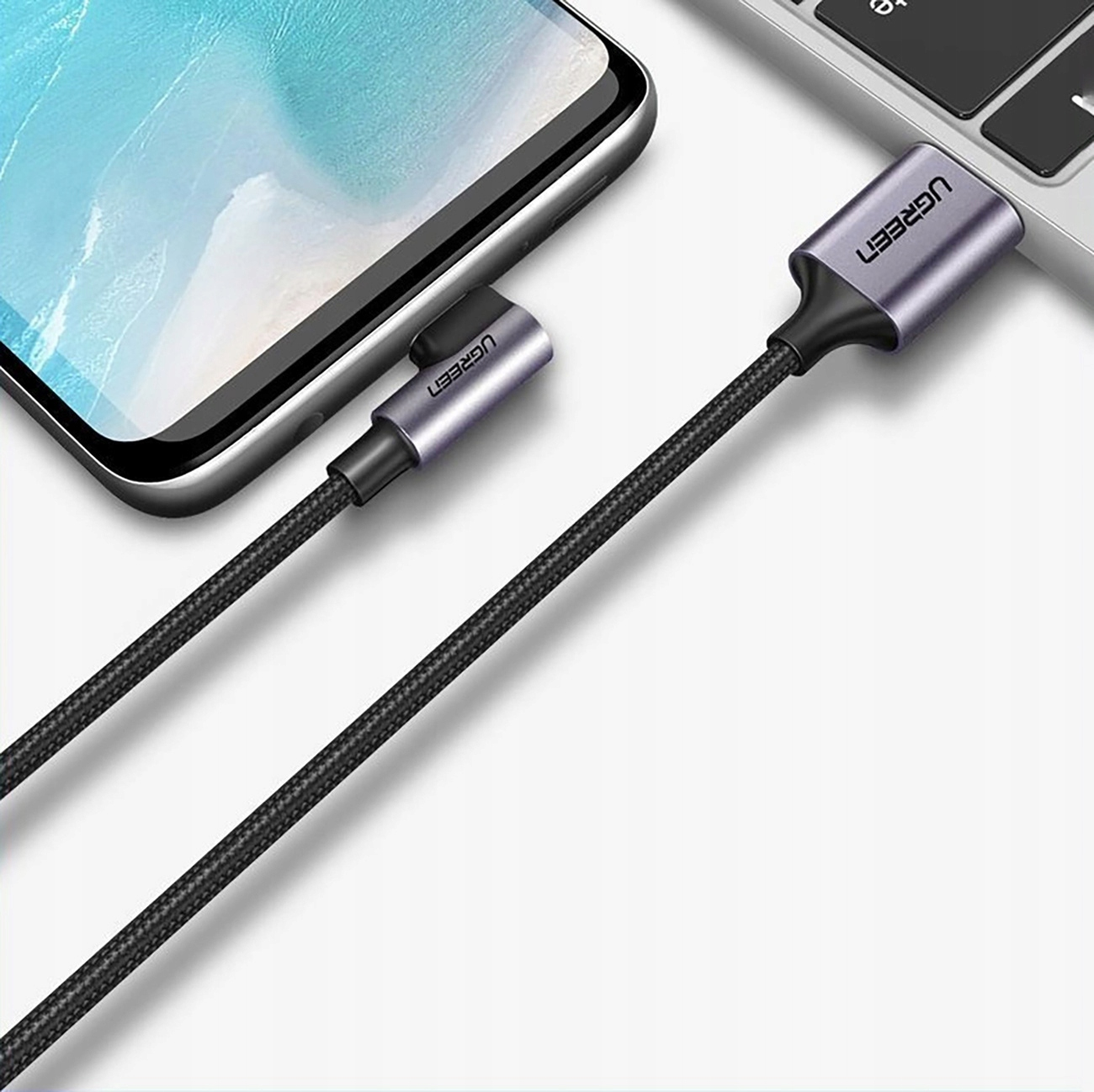 Kabel USB-C do USB podłączony do telefonu i laptopa. Kabel jest czarny, a złącza srebrne.