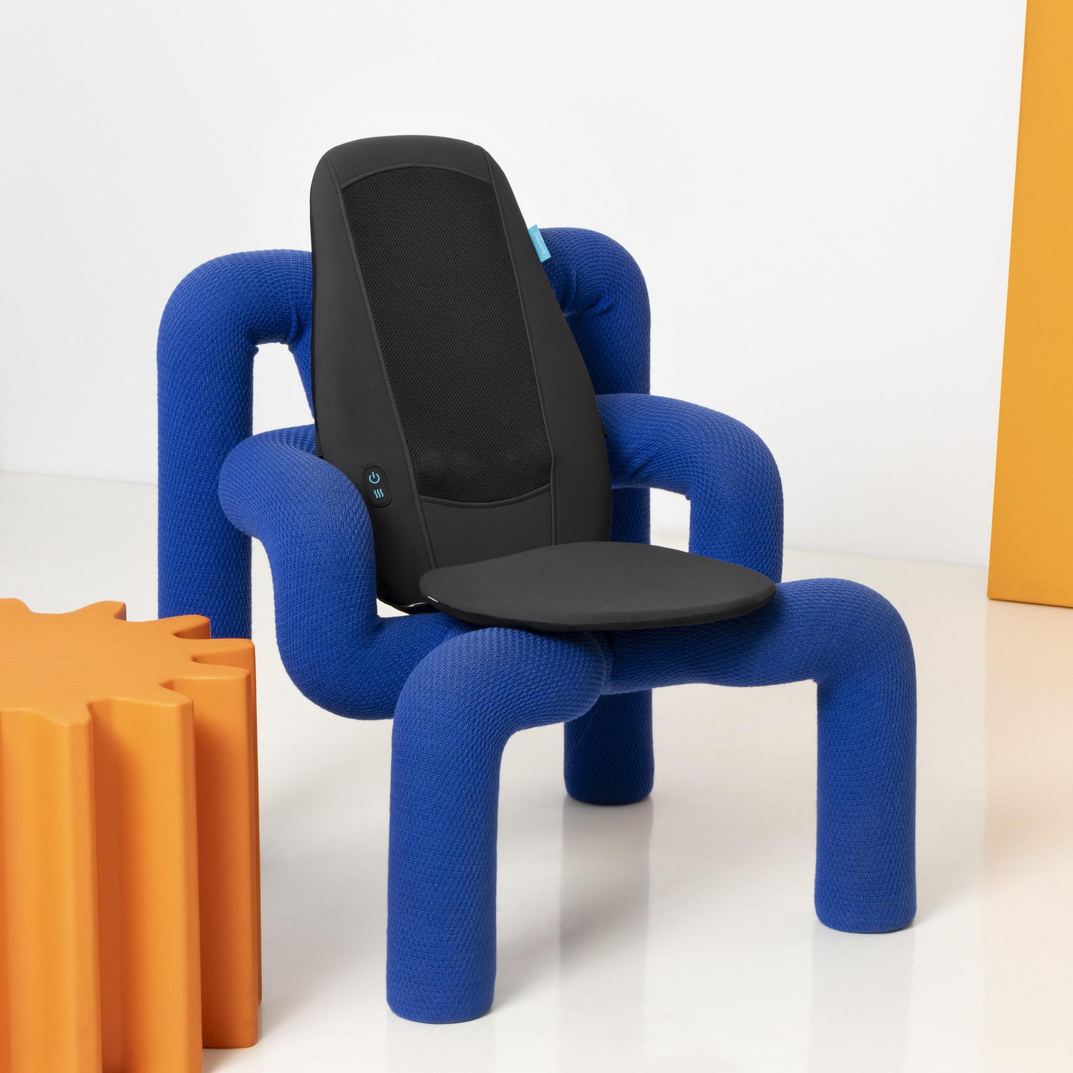 Czarna poduszka do masażu na niebieskim, zakrzywionym krześle. Pomarańczowy obiekt w kształcie koła zębatego.