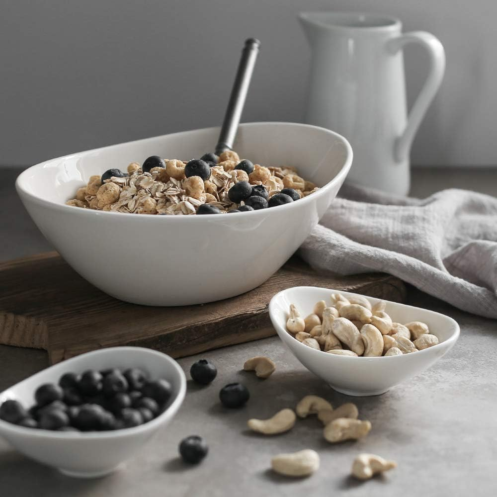 Ciotola per la colazione con cereali e mirtilli, altre ciotole con noci e mirtilli.