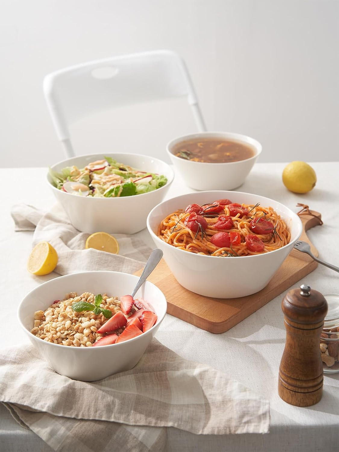 Una tavola imbandita con ciotole di cibo, tra cui insalata, pasta e una ciotola con frutta e cereali.
