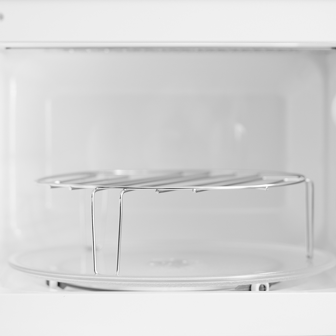 Wnętrze białej kuchenki mikrofalowej. Widoczny talerz obrotowy, a nad nim metalowa kratka.