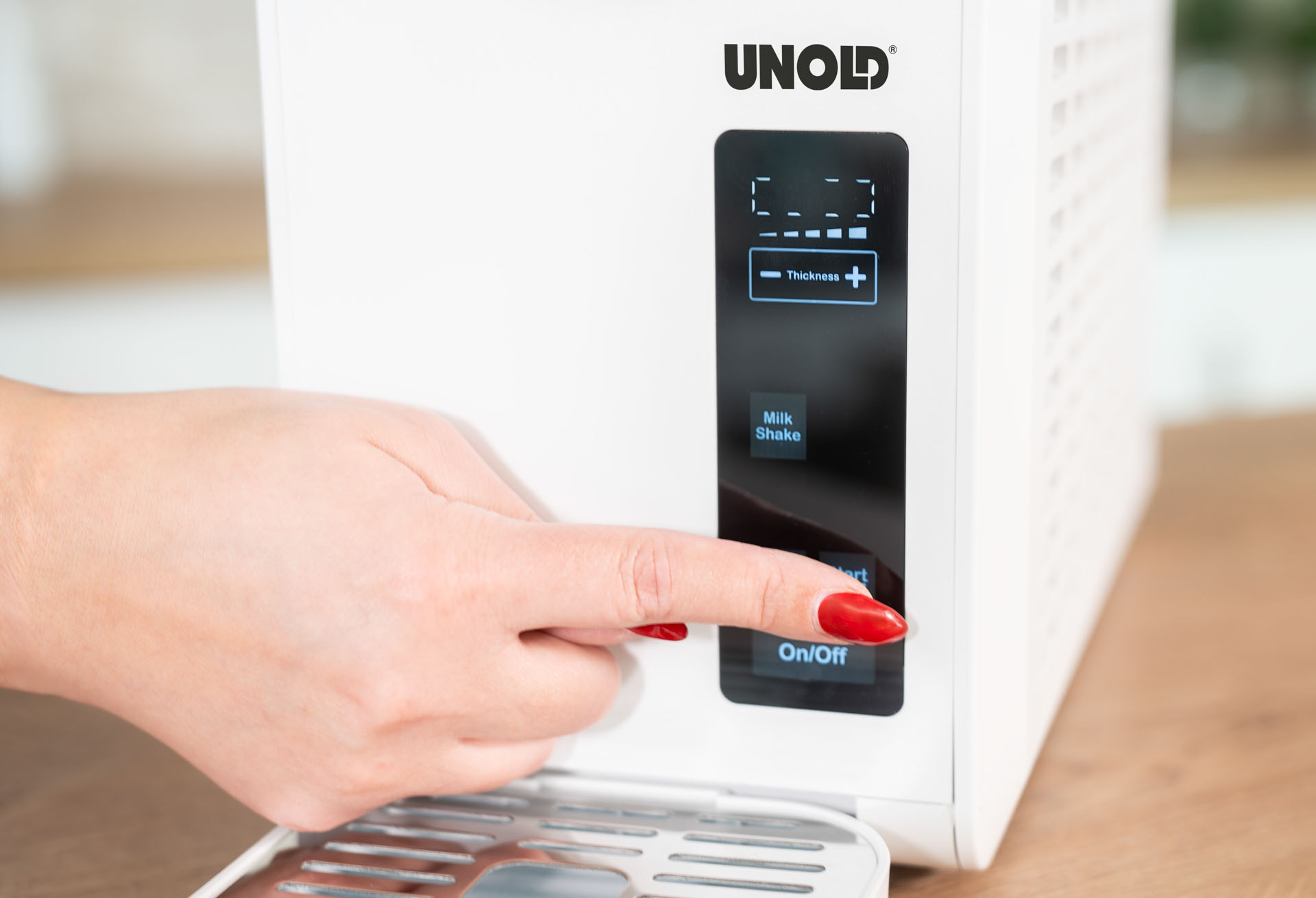 Dłoń kobiety naciska przycisk włączania/wyłączania na białym urządzeniu.