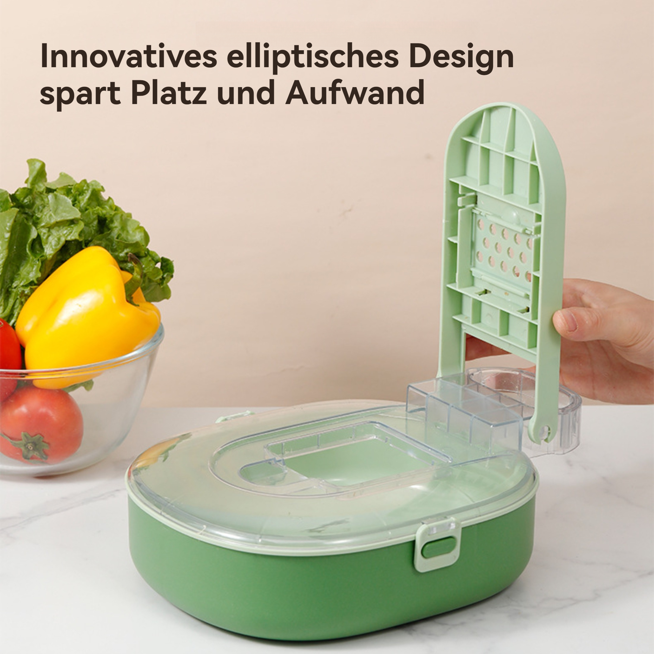 Ein grüner Gemüseschneider mit Griff, offen, mit einer gelben Paprika und Tomate in der Nähe.