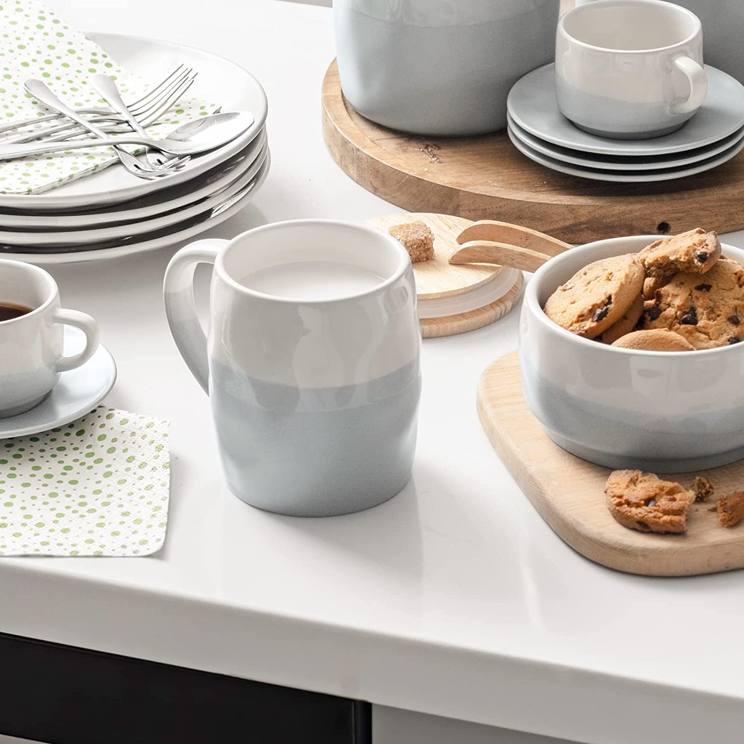 Una tazza e una ciotola con biscotti. Sono visibili anche una tazzina di caffè e un tovagliolo a pois.