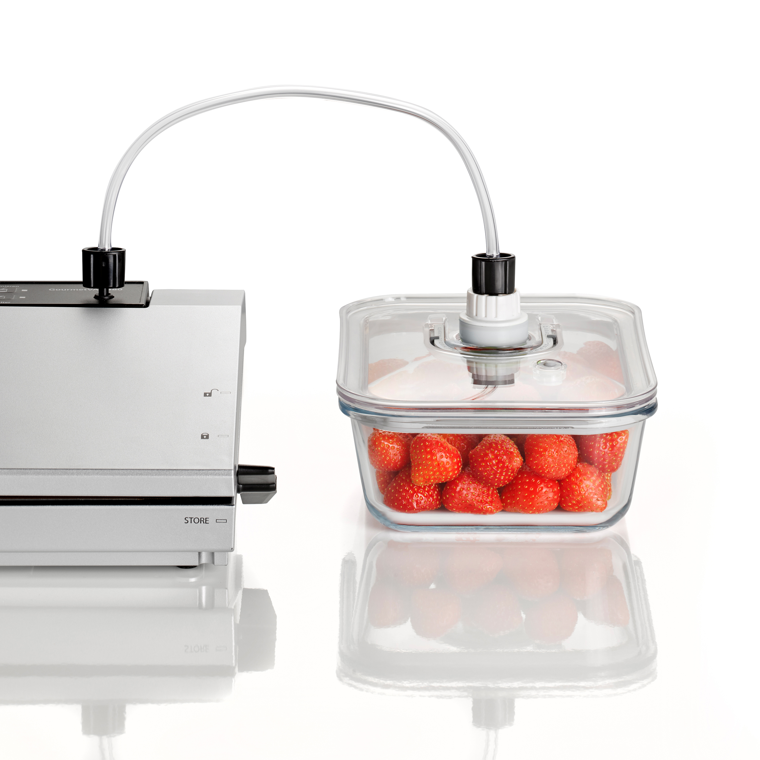 Eine Vakuumversiegelungsmaschine mit einem Glasbehälter, der mit Erdbeeren gefüllt ist, verbunden.