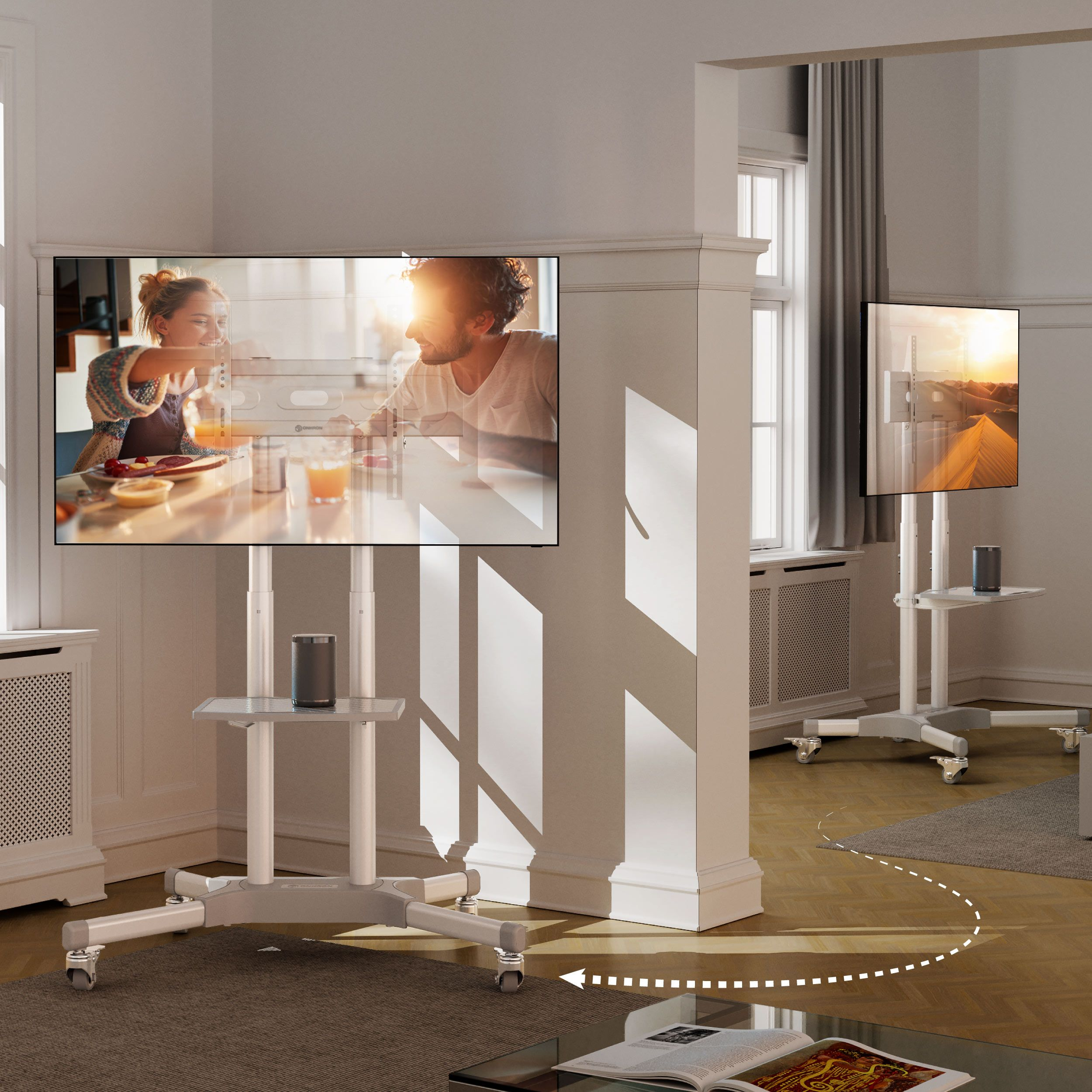 Dwa telewizory na białych stojakach w pokoju. Widać parę, a książka jest otwarta na stole.