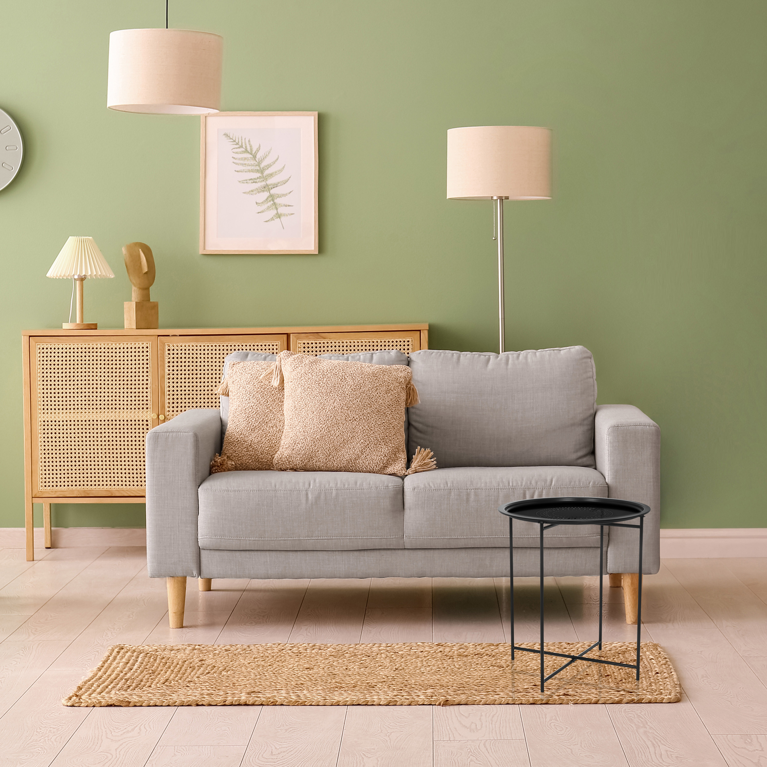 Wohnzimmer mit grauem Sofa, schwarzem Beistelltisch, Teppich, Holzschrank und Lampen. Grüne Wand.