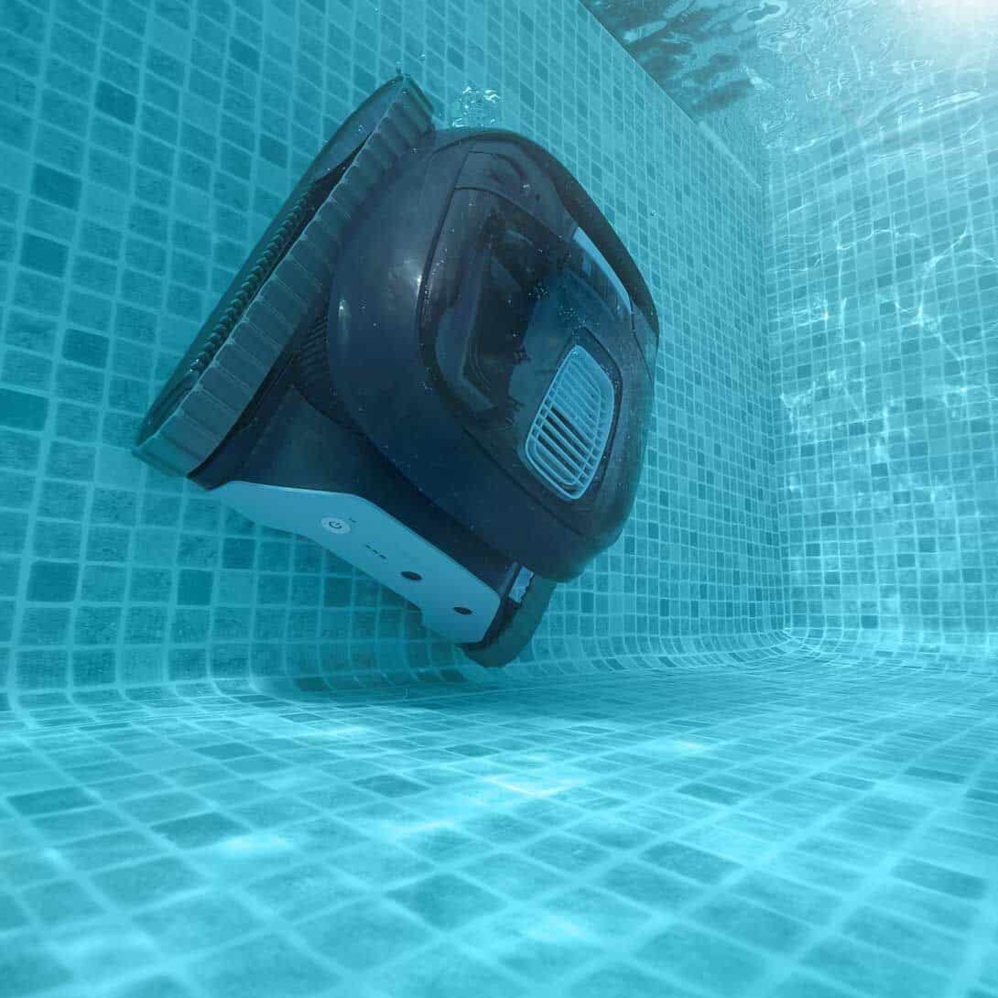 Un robot limpiador de piscinas en una piscina, vista en ángulo, mostrando la parte inferior y las orugas.