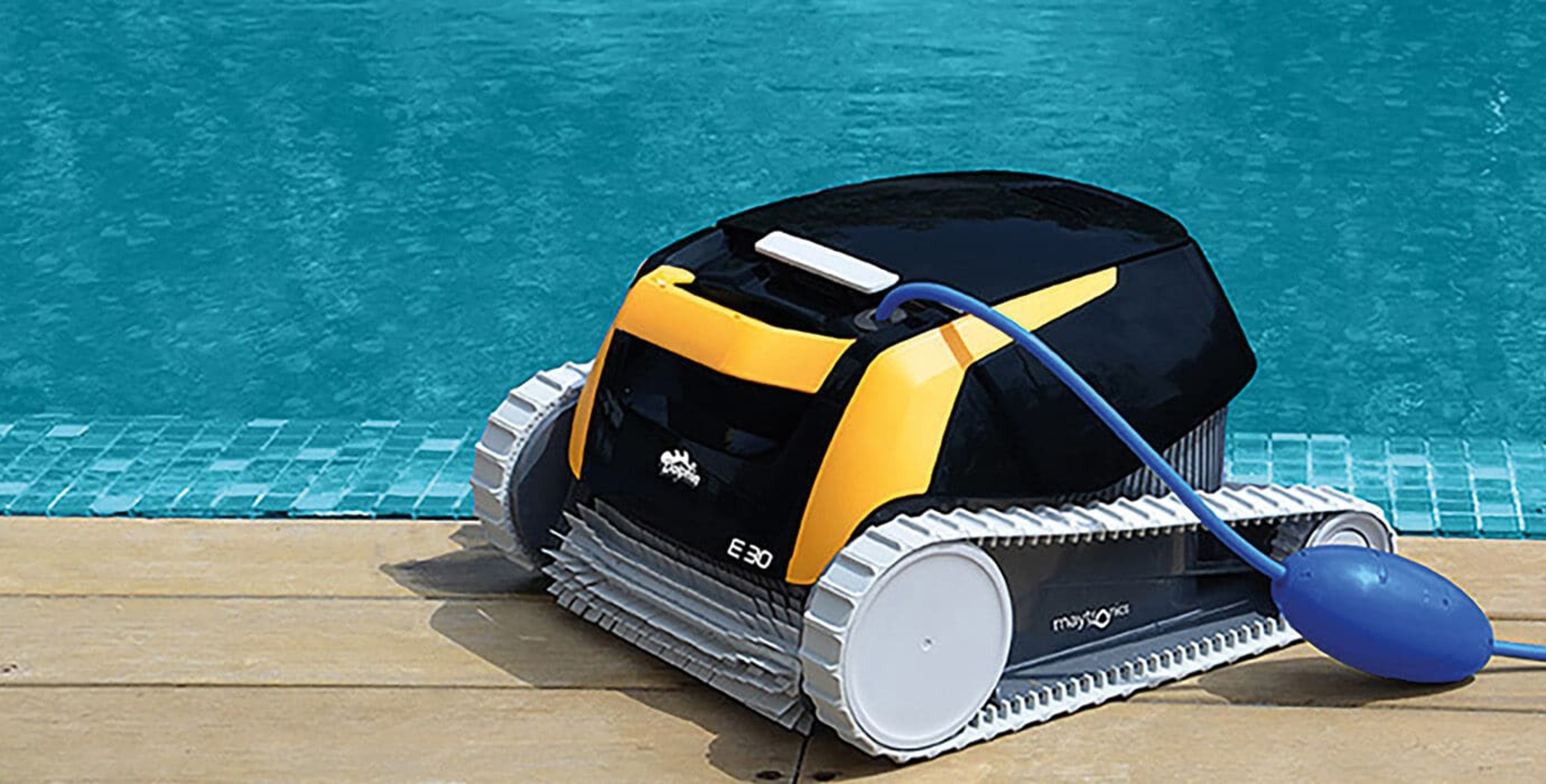 Un robot limpiador de piscinas está al borde de una piscina, con una manguera azul.