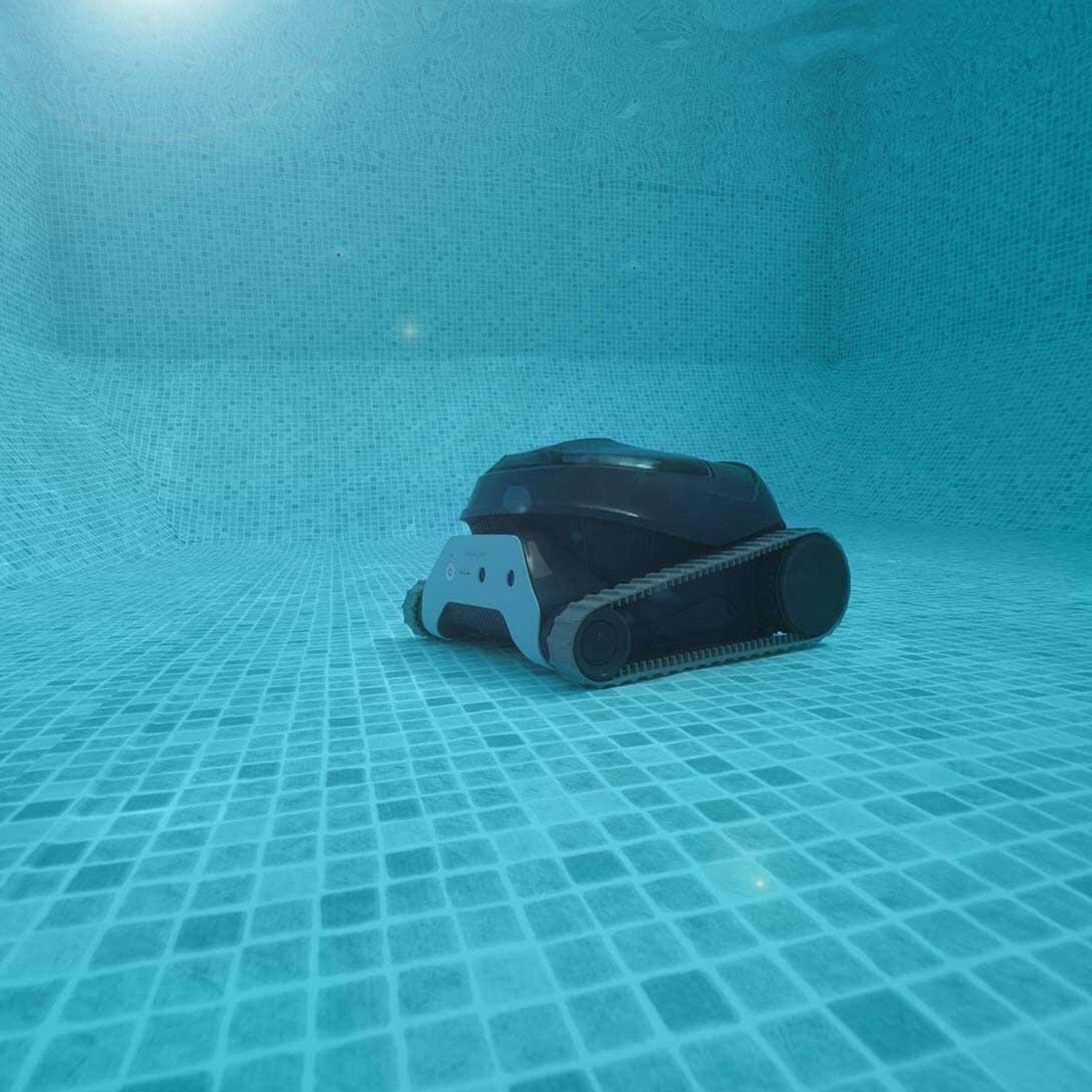 Un robot limpiador de piscinas negro y gris sumergido en una piscina.