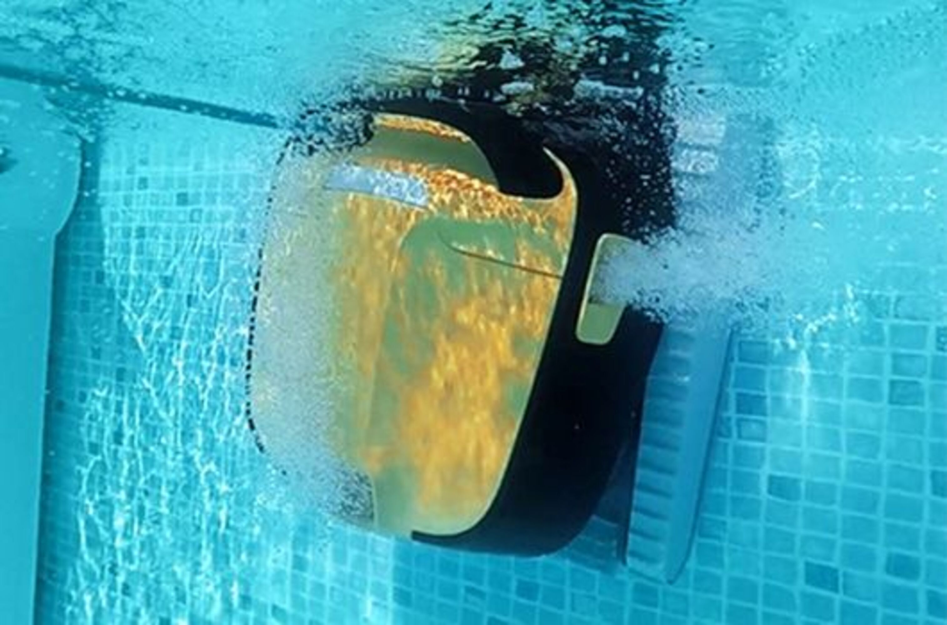 Un robot limpiador de piscinas está en el agua, creando burbujas y limpiando.