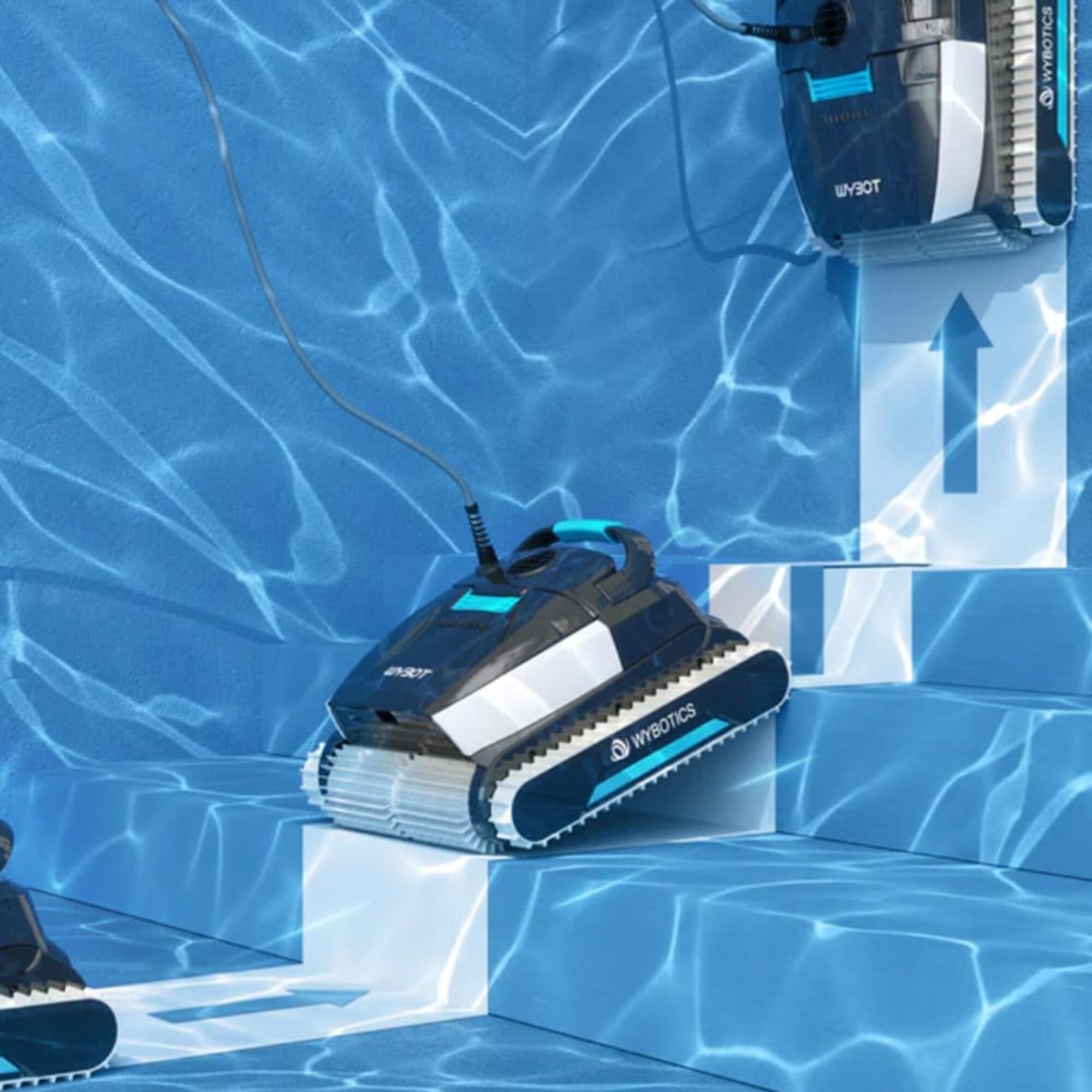Un robot limpiador de piscinas sentado en escalones en una piscina. El robot es negro y verde azulado con el logo 'WYBOTICS'.