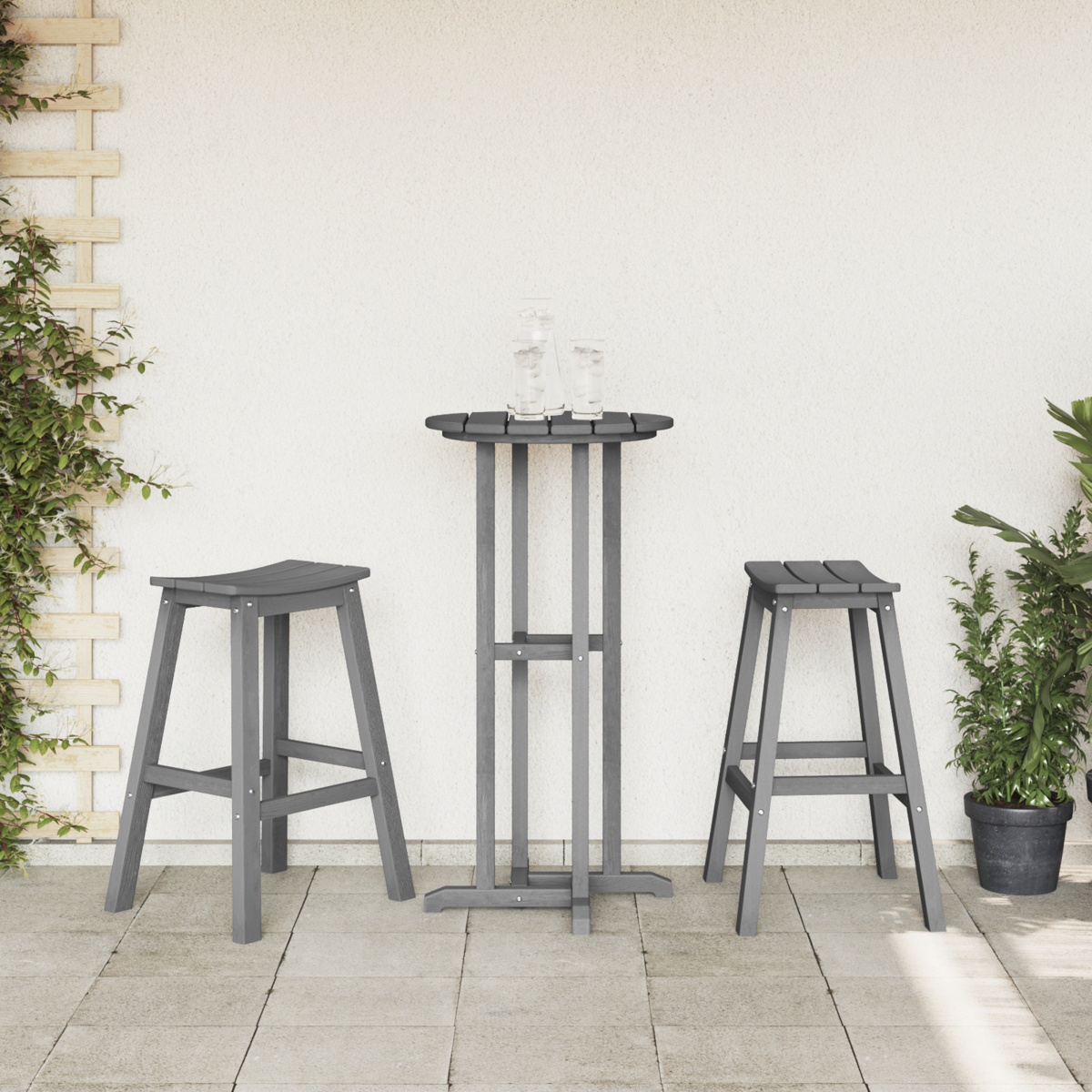 Zwei Hocker und ein hoher grauer Tisch mit Getränken. Die Szene spielt auf einer Terrasse mit Pflanzen und Wand.
