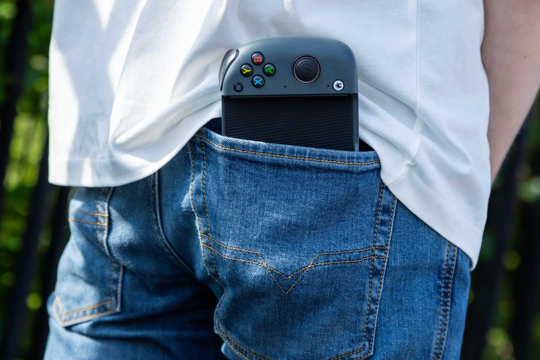 Kieszeń dżinsów z kontrolerem do gier częściowo w środku. Kontroler jest ciemnoszary. Tło jest rozmyte.