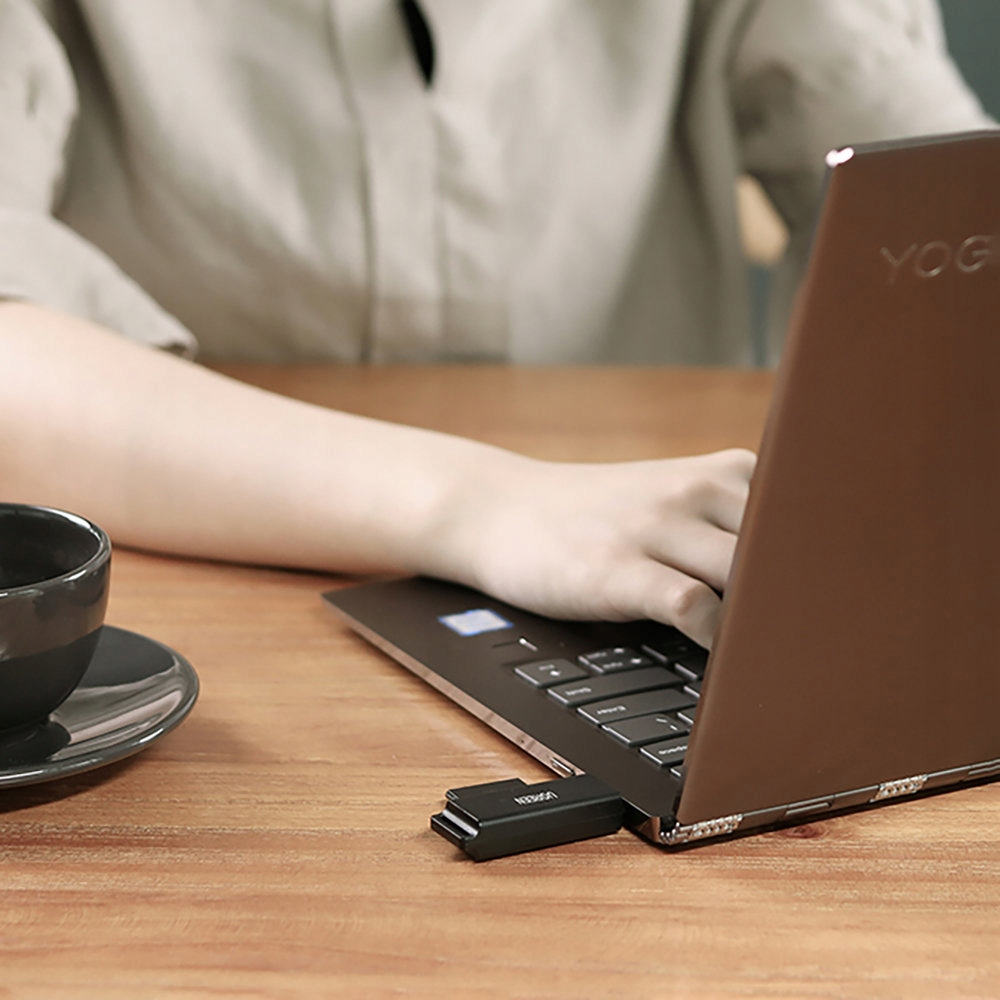 Laptop z podłączonym kluczem USB, na drewnianym stole z filiżanką.