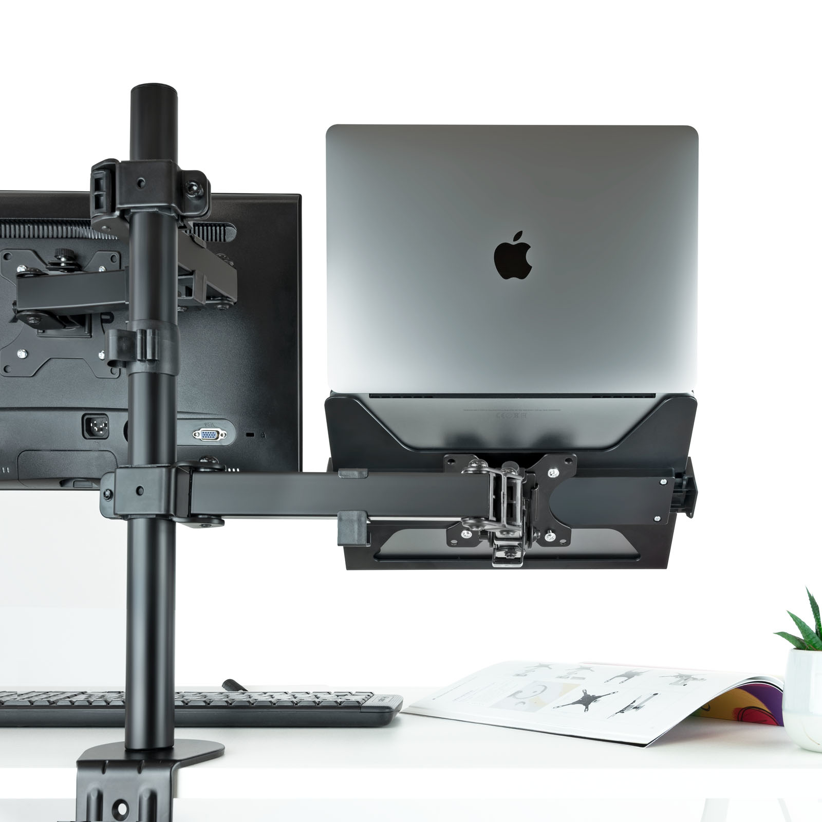 Ein Laptop auf einem schwarzen Ständer mit Monitor und Tastatur.