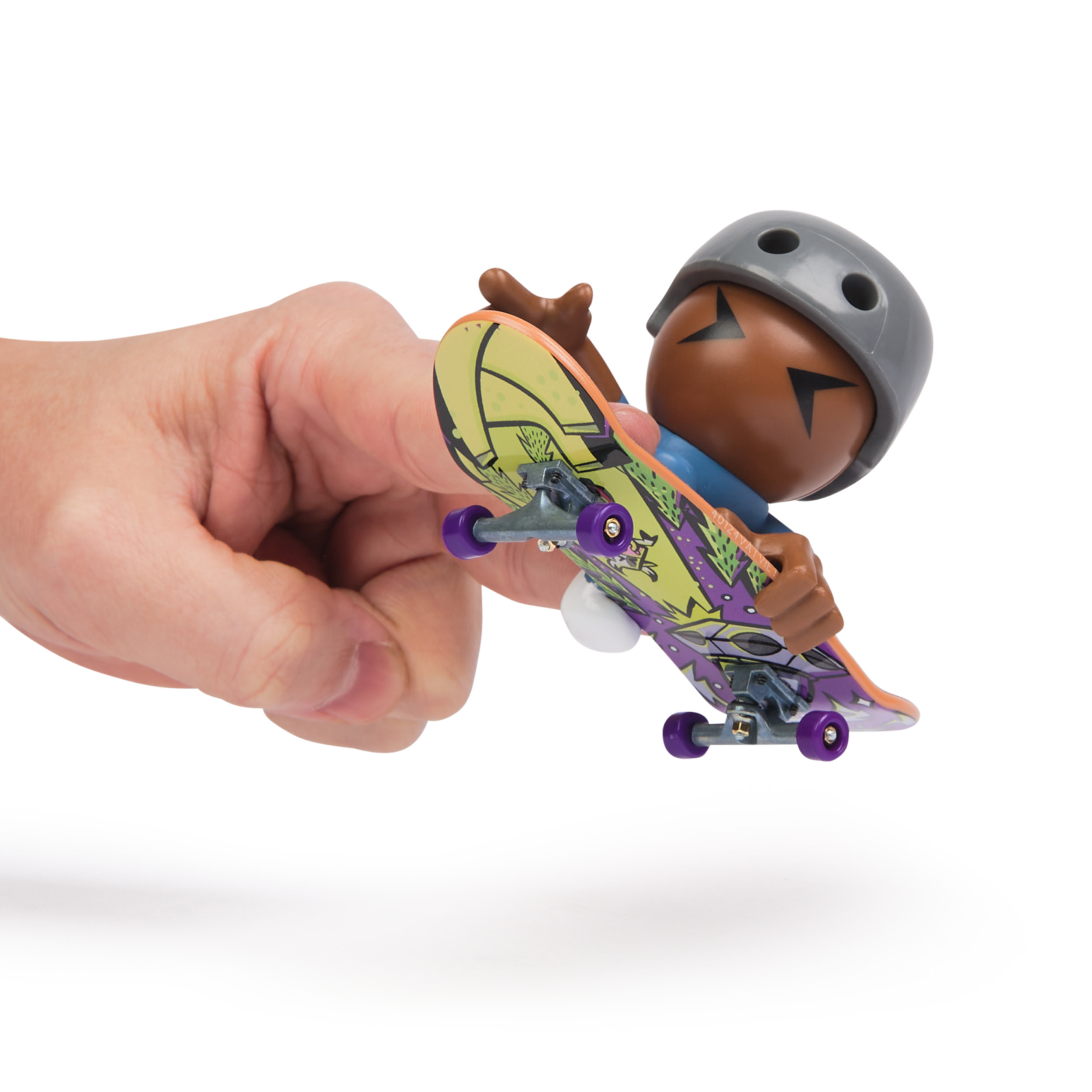 Una mano sosteniendo un pequeño monopatín de juguete con una figura de dibujos animados que lleva un casco.