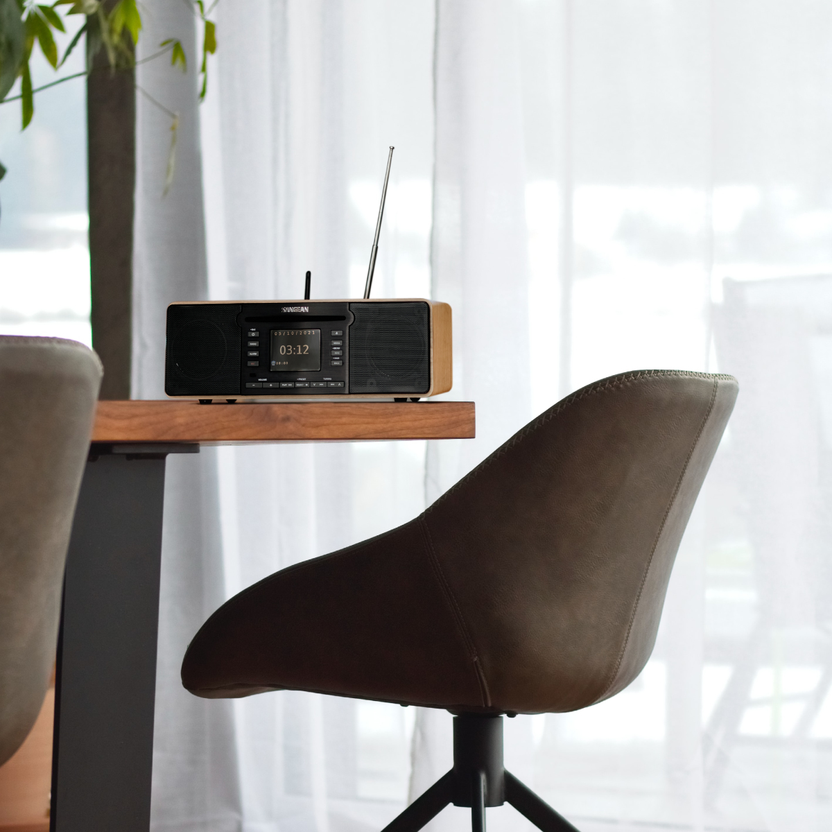 Una radio di legno su un tavolo. Una sedia in primo piano. Finestra e luce sullo sfondo.