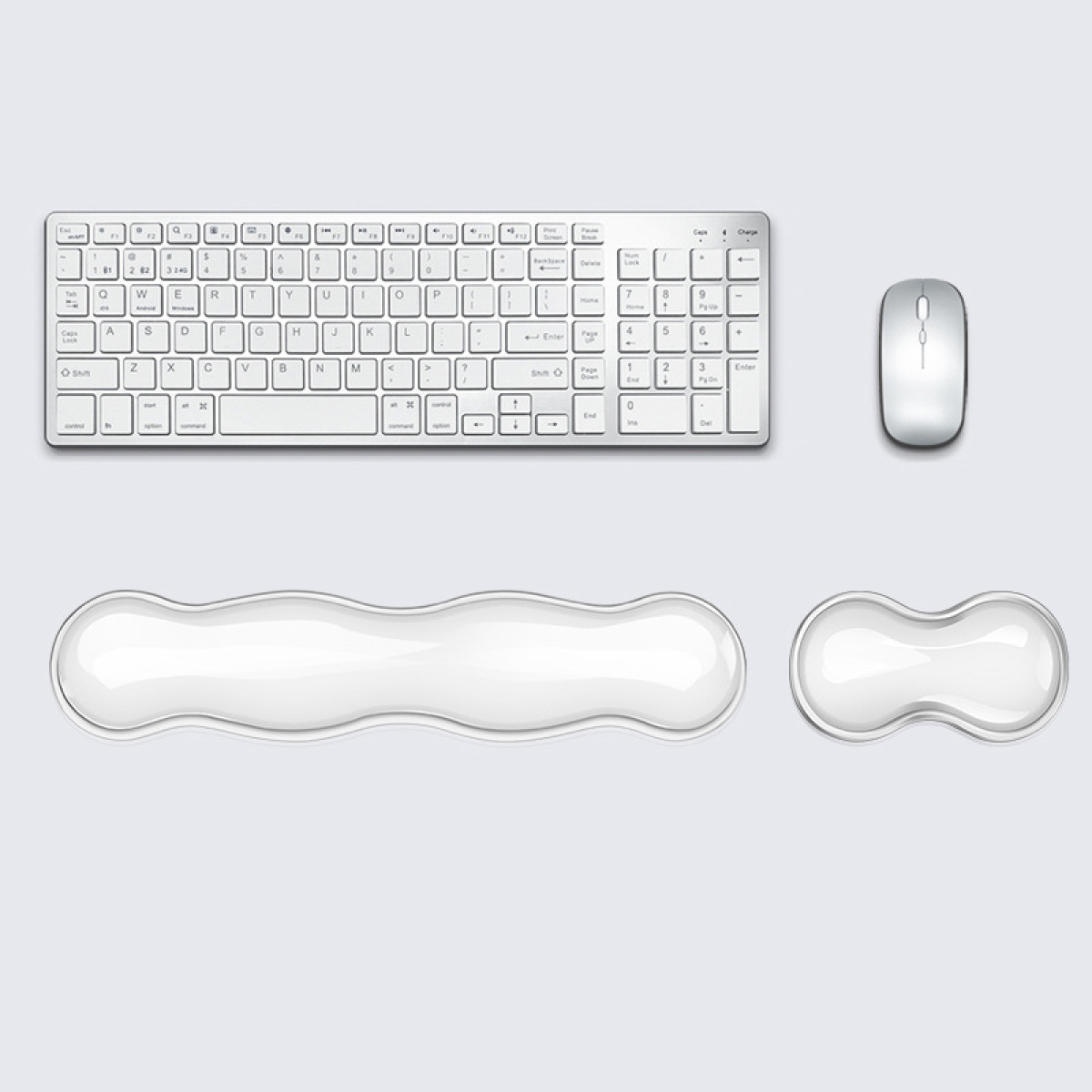 Una tastiera, un mouse e due poggiapolsi bianchi su una superficie grigio chiaro. La tastiera è wireless.