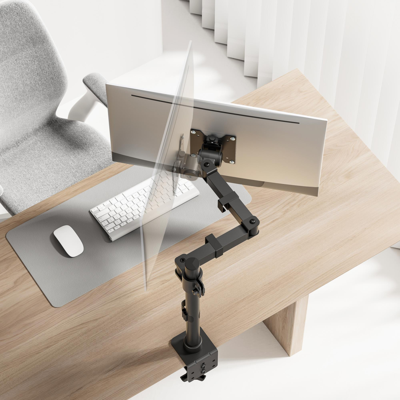 A computer monitor on a wooden desk. A gray chair sits behind the desk. A white keyboard and mouse are on the desk.