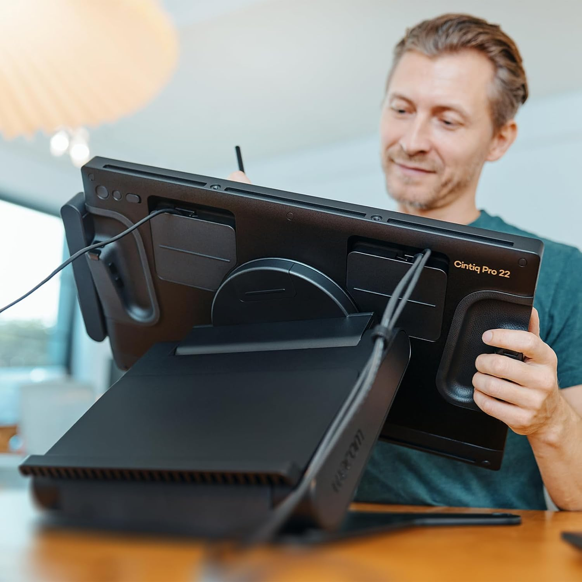 Una persona tiene in mano una Wacom Cintiq Pro 22, che poggia su un supporto. La persona sorride.