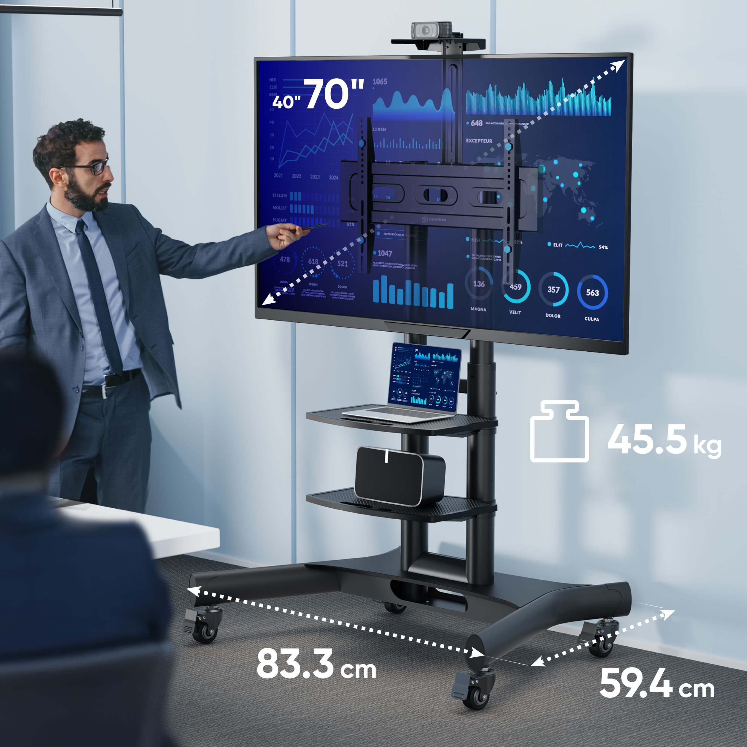 Homme pointant vers une télévision sur un support mobile. L'écran affiche des données, un ordinateur portable sur l'étagère. Dimensions et poids fournis.
