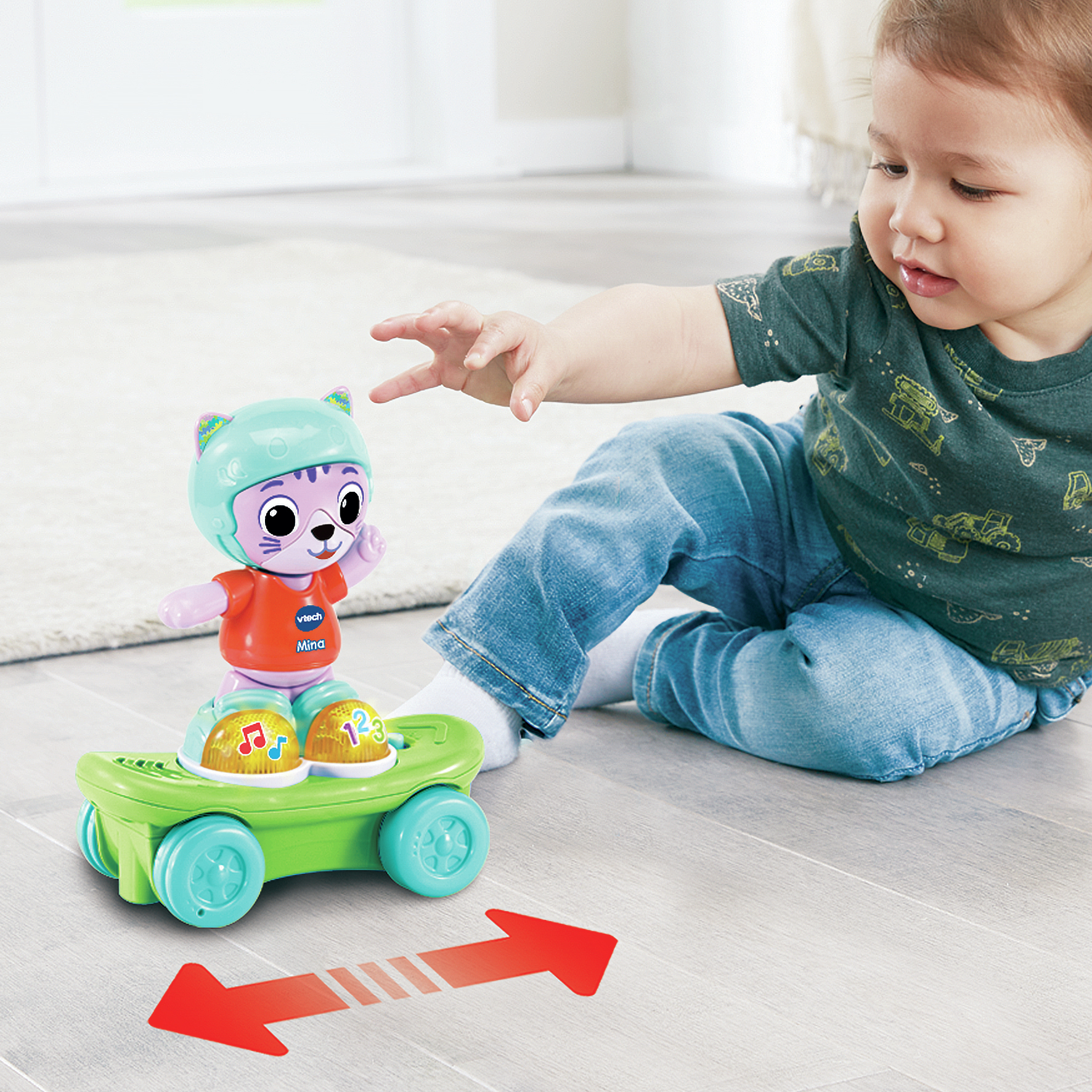 Ein Kind spielt mit einer Spielzeugkatze auf einem Skateboard. Das Spielzeug bewegt sich.
