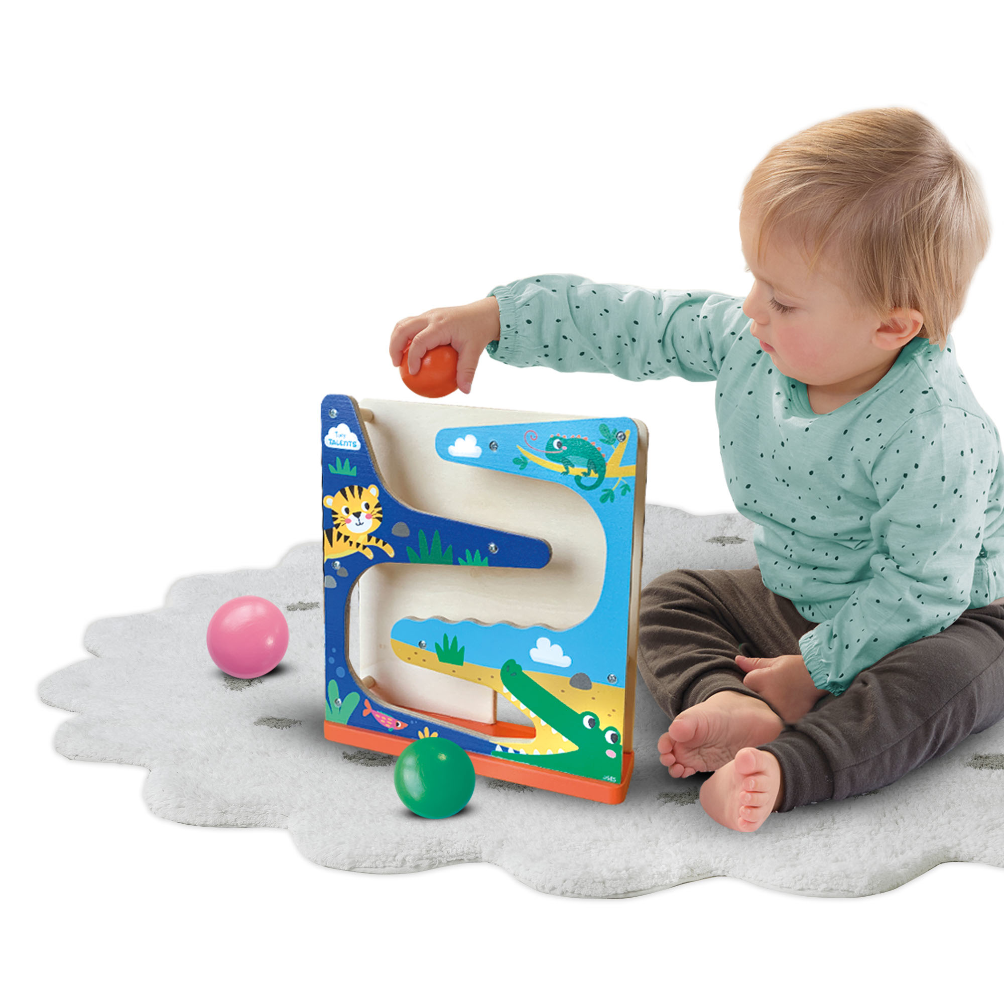 Ein Baby spielt mit bunten Bällen und einem Holzspielzeug mit Krokodil-Design.